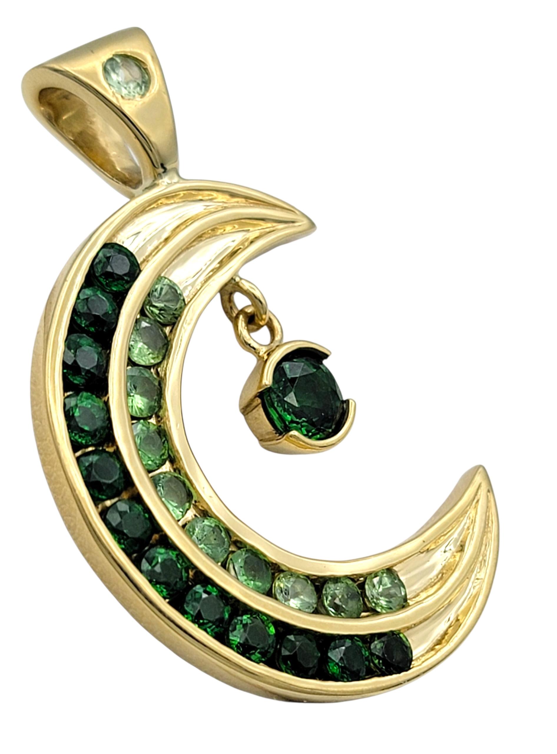This captivating tsavorite pendant features a bold crescent moon design that beautifully curves around a deep green gemstone at its center. The moon’s surface glimmers with a constellation of smaller tsavorites, creating a mesmerizing play of dark