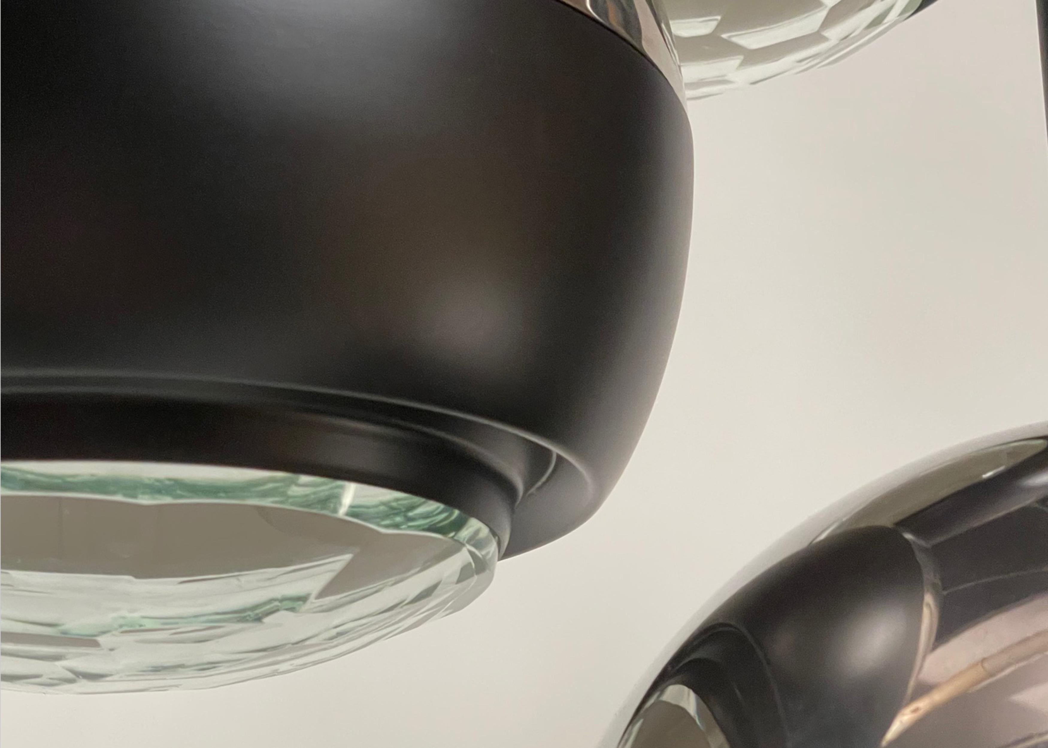 Three light fixture in chromed and black painted metal, with facetted glass discs at the bottoms.