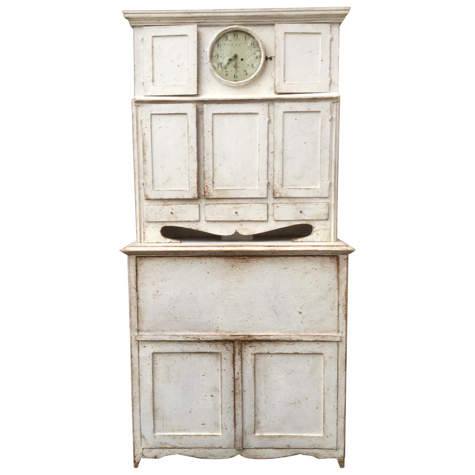 Swedish light gray Gustavian clock cupboard with drop-front desk, circa 1810.

Clock complete with pendulum and weights. Working mechanism, however not tested. Cabinet built in 2 parts for easier handling.

We offer low cost front door delivery to