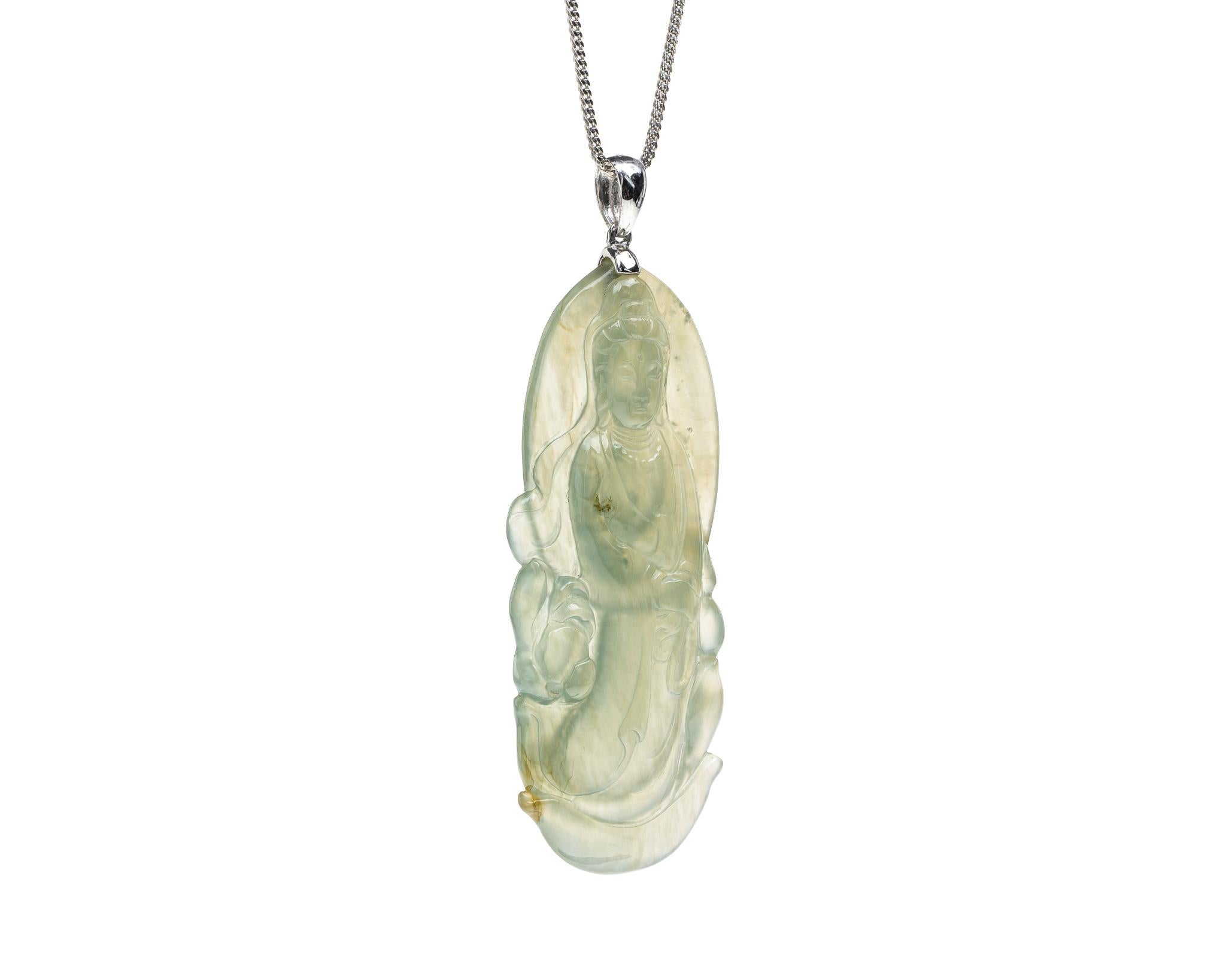 This is an all natural, untreated green jadeite jade carved Quan Yin god pendant set on an 18K white gold bail.  The carved Quan Yin god symbolizes compassion and protection. 

It measures 2.28 inches (58 mm) x 0.84 inches (21.3 mm) with thickness