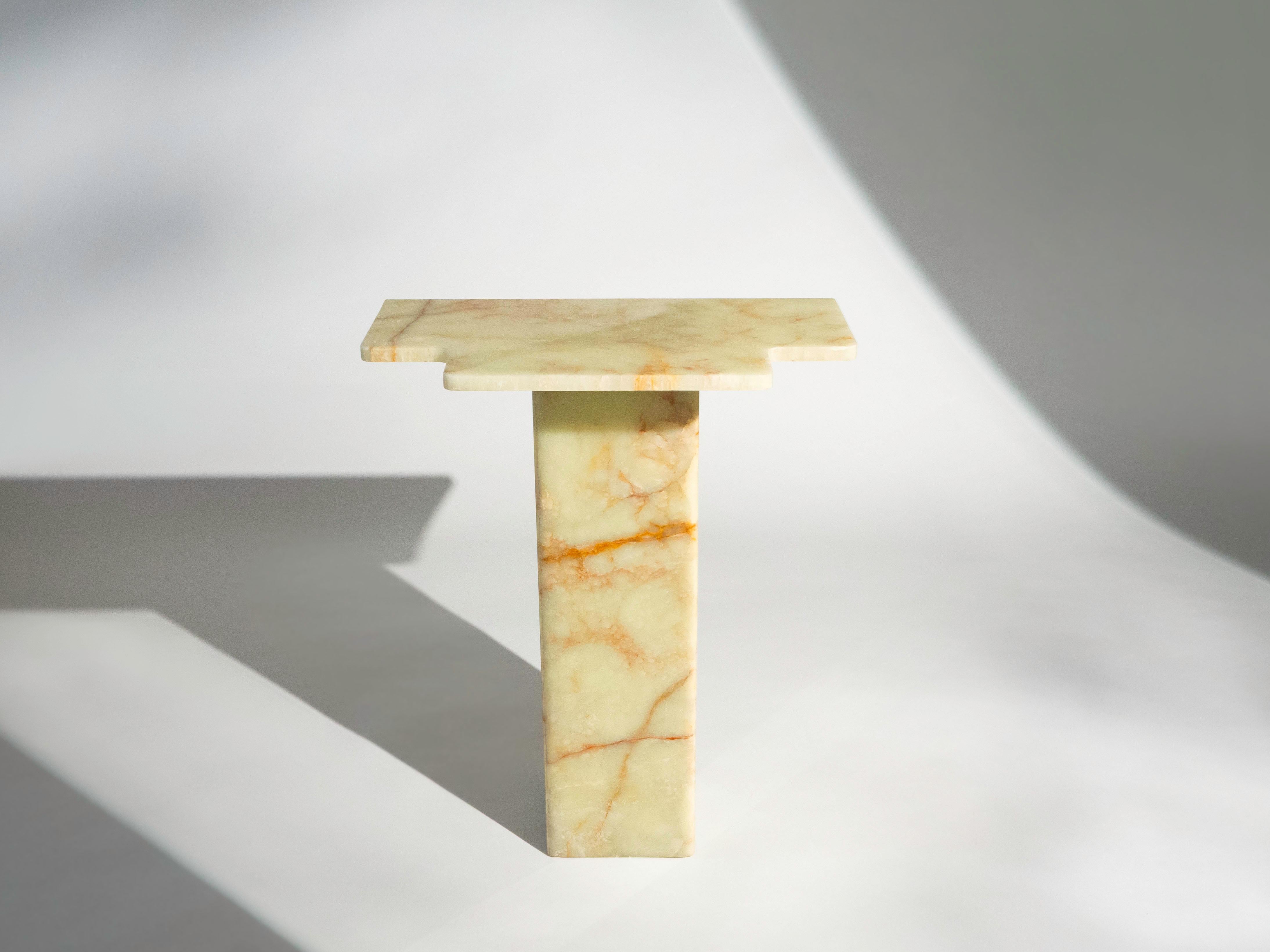 This display pedestal table is made from solid, light green onyx. It is finished with smooth, round edges. The veining of the stone ranges from mossy green tones, amber and golden hues, as well as light cream marbling throughout.

The table is