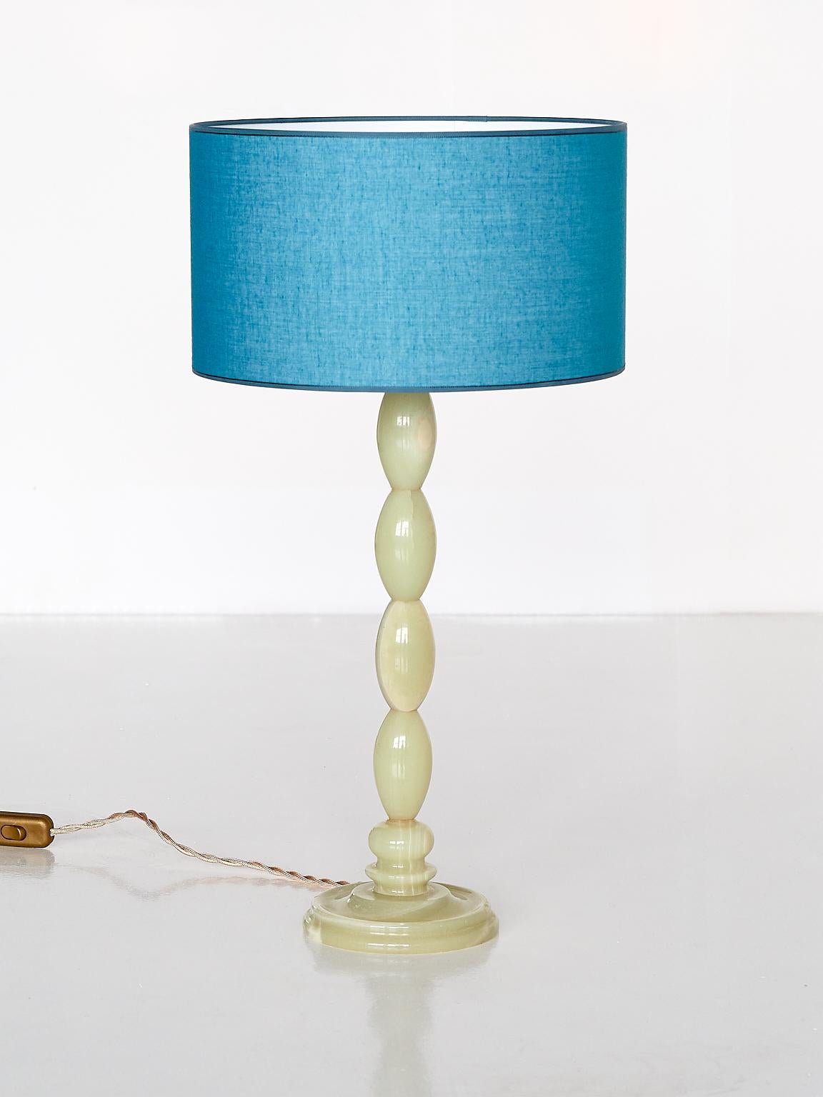 This elegant table lamp was produced in France in the late 1970s. The base consists of four stacked oval shapes, resting on a circular foot, all in light green onyx. The newly made blue shade allows for a pleasant and warm light distribution when