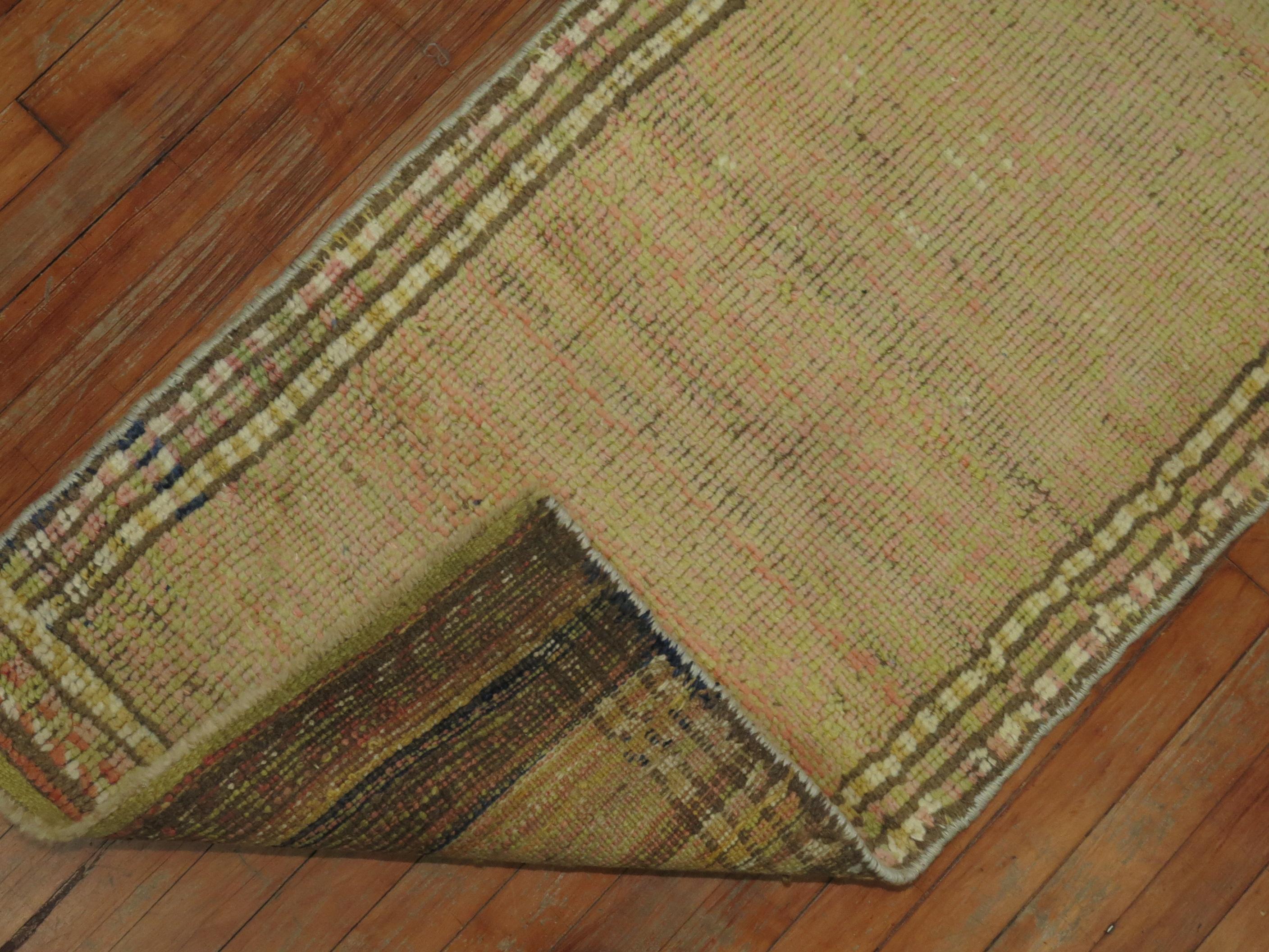 A mid-20th century Turkish runner with a beige green color open field design with specks of pink throughout encased by multiple narrow borders

circa 1940, measures: 2'2