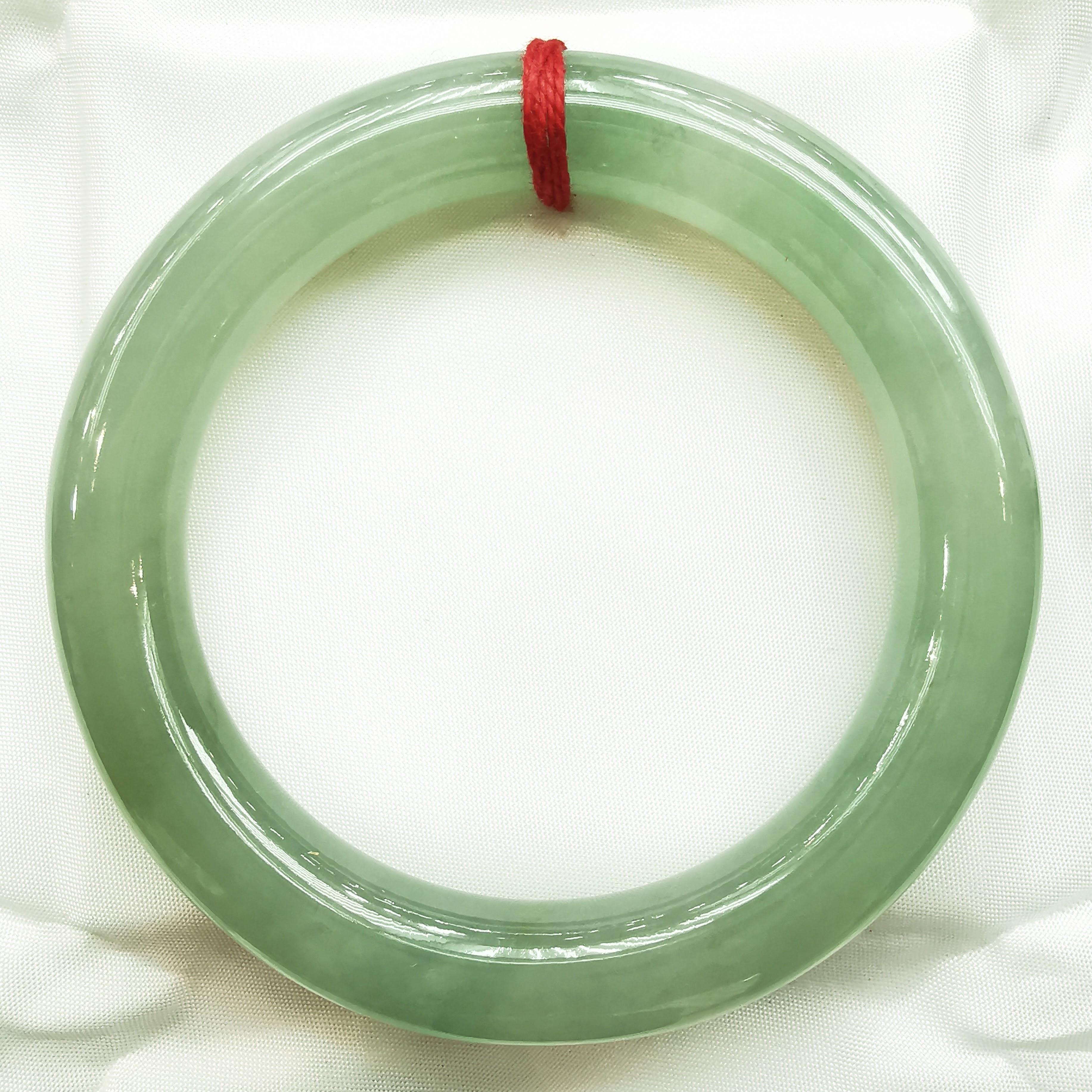 Introducing our Genuine Burmese Light Green Thick Jade Bangle, a stunning piece that exudes natural beauty and elegance. This exquisite bangle is crafted from genuine Burmese jade, known for its exceptional quality and captivating light green