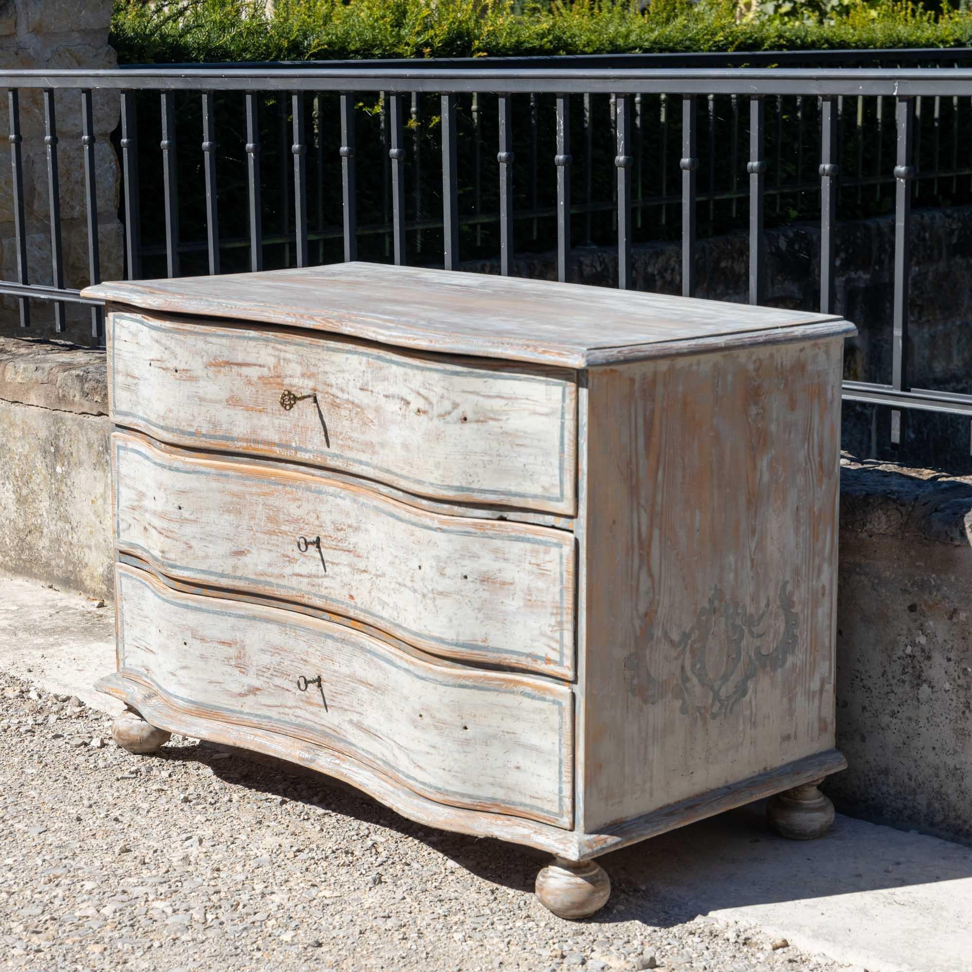 Hand-painted baroque chest of drawers in light grey with blue accents. The corpus with serpentine front stands on lightly pressed ball feet. The painting is new and was inspired by historical models.