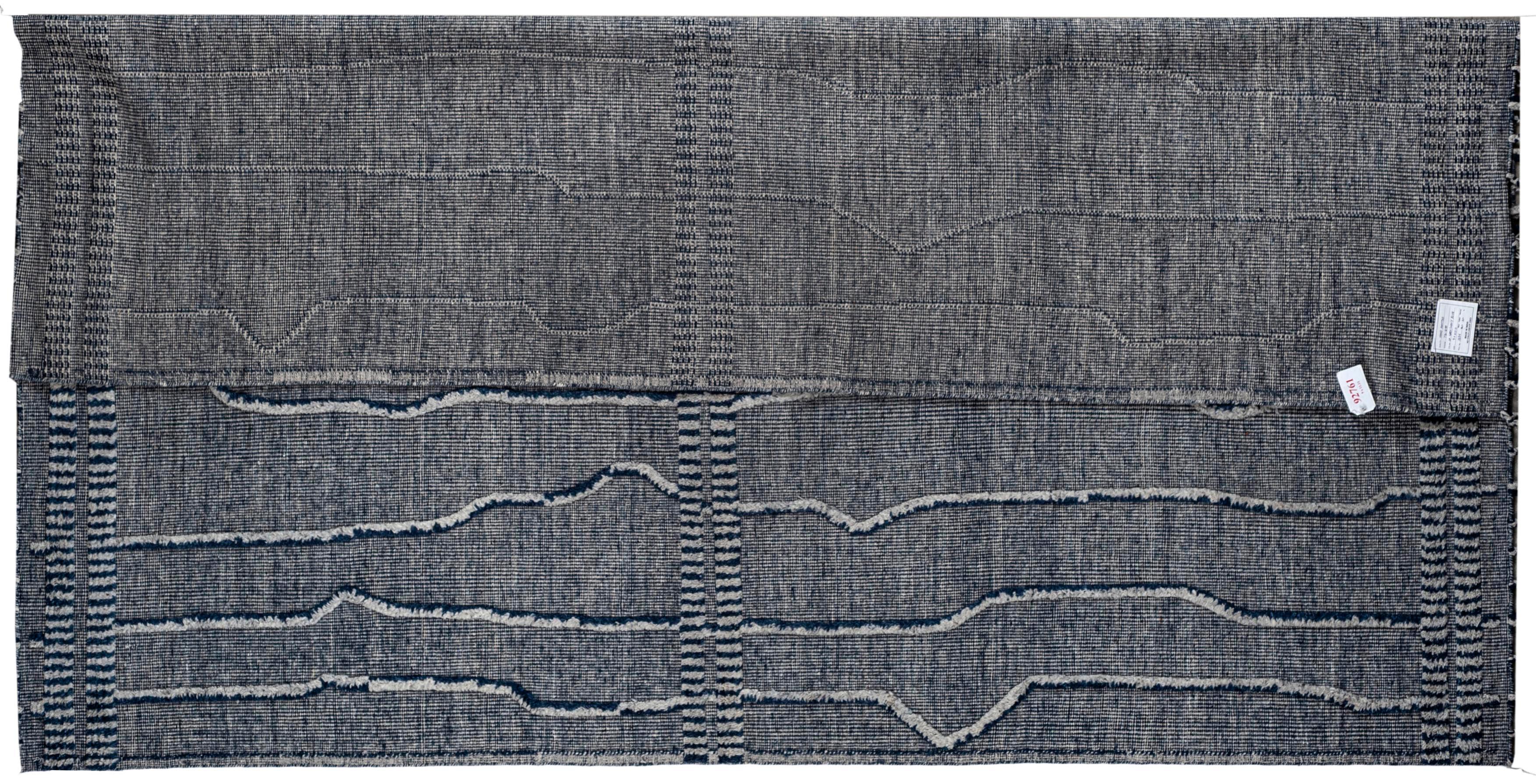 Coming from our newest collection of Moroccan designs, this 9x12 light grey and navy blue striped Moroccan design area rug is handmade and hand-knotted made in India. It has a cotton base and is made from all wool yarns. It features a contemporary