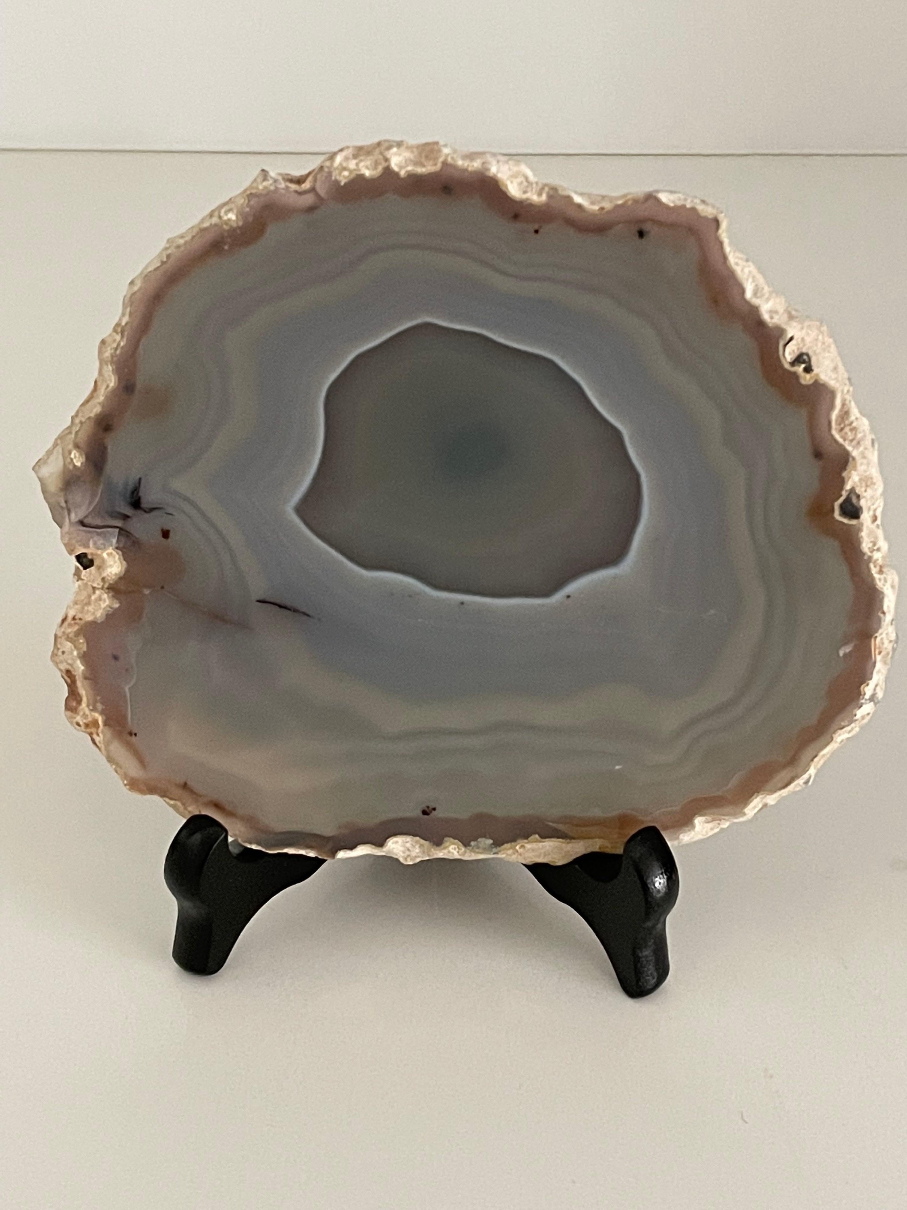 Brazilian thin slice of agate mounted on a wood stand.
Agate is a banded form of finely-grained, microcrystalline Quartz. 
The lovely color patterns and banding make this translucent gemstone very unique. 
Agates can have many distinctive styles