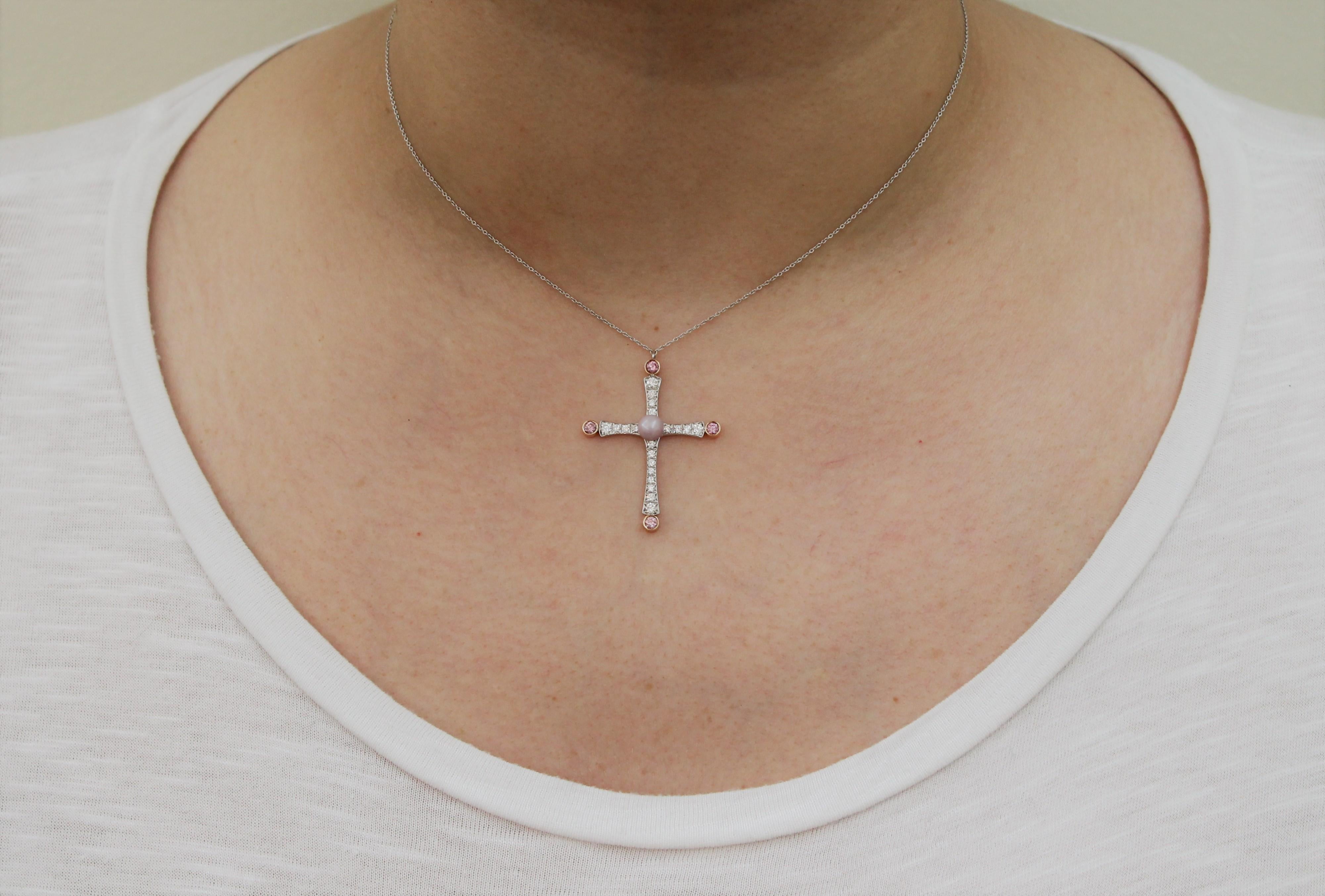 This Byzantine-inspired Hand-made Cross Pendant Necklace features a Light Lilac Quahog Pearl of 0.79 Carat in the centre of the Cross. 
The delicate arms of the cross are studded with White Diamonds and at their ends are 4 Pink Argyle Round Diamond,