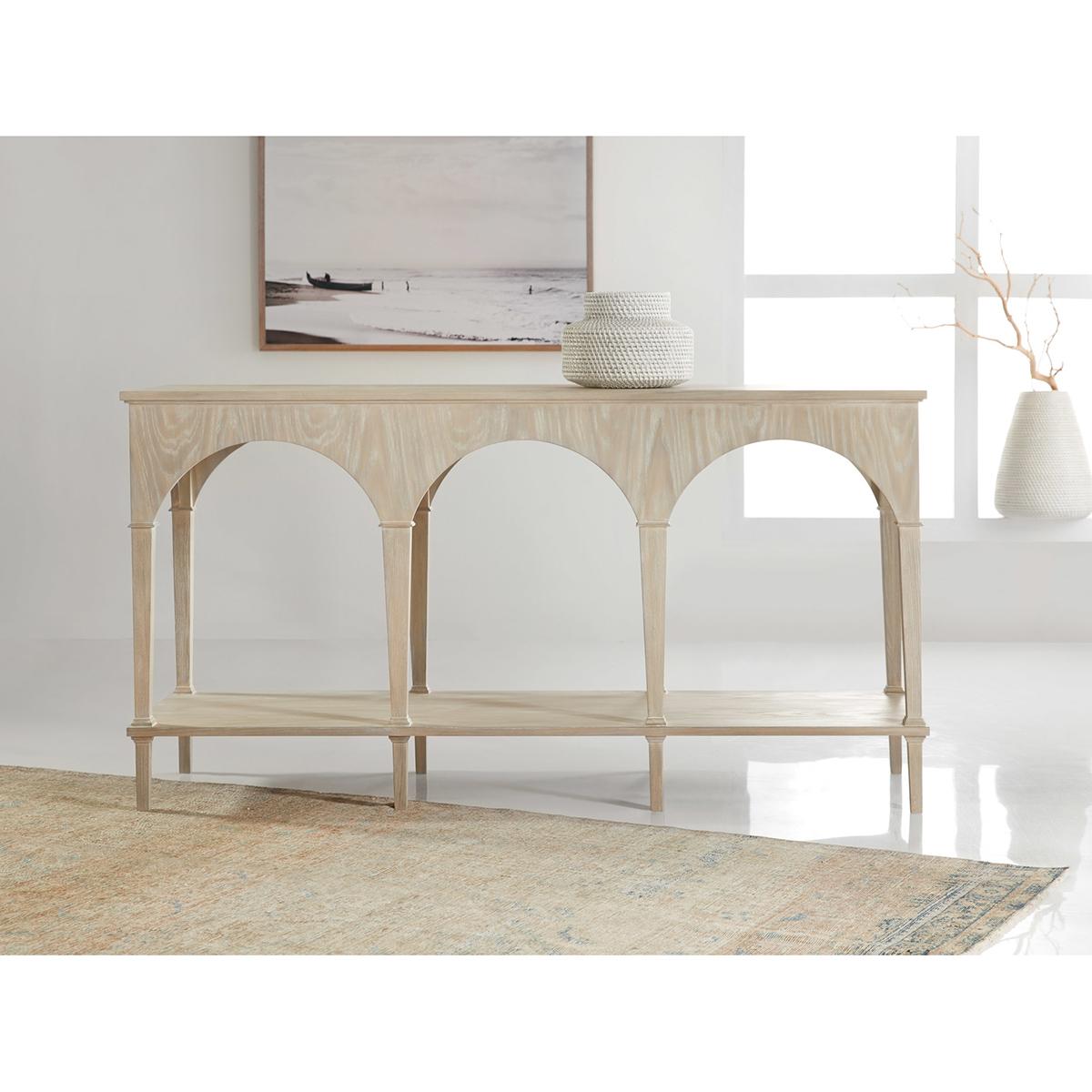 Modern Console Table with a light whitewashed ash veneer. The large modern table takes design cues from the 18th-century Gothic style with its arched doorway design. A rectangular table with eight tapered legs and a shelf stretcher