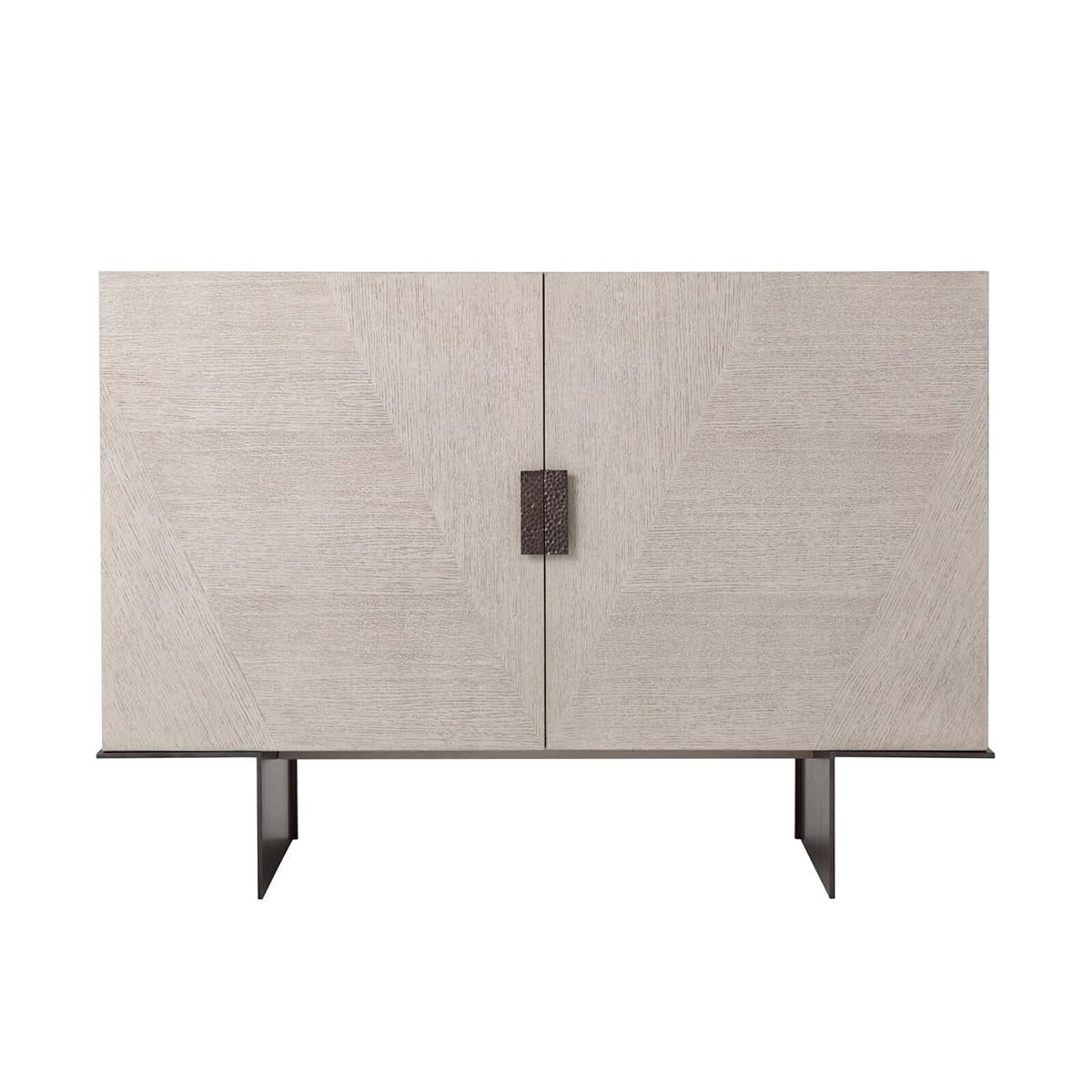 Light oak Modern media cabinet, in our brushed oak Gowan finish with a subtle chevron parquetry detail on the doors. The split interior with an adjustable shelf on one side and central drawer on the other. The cabinet is raised on a cantilevered