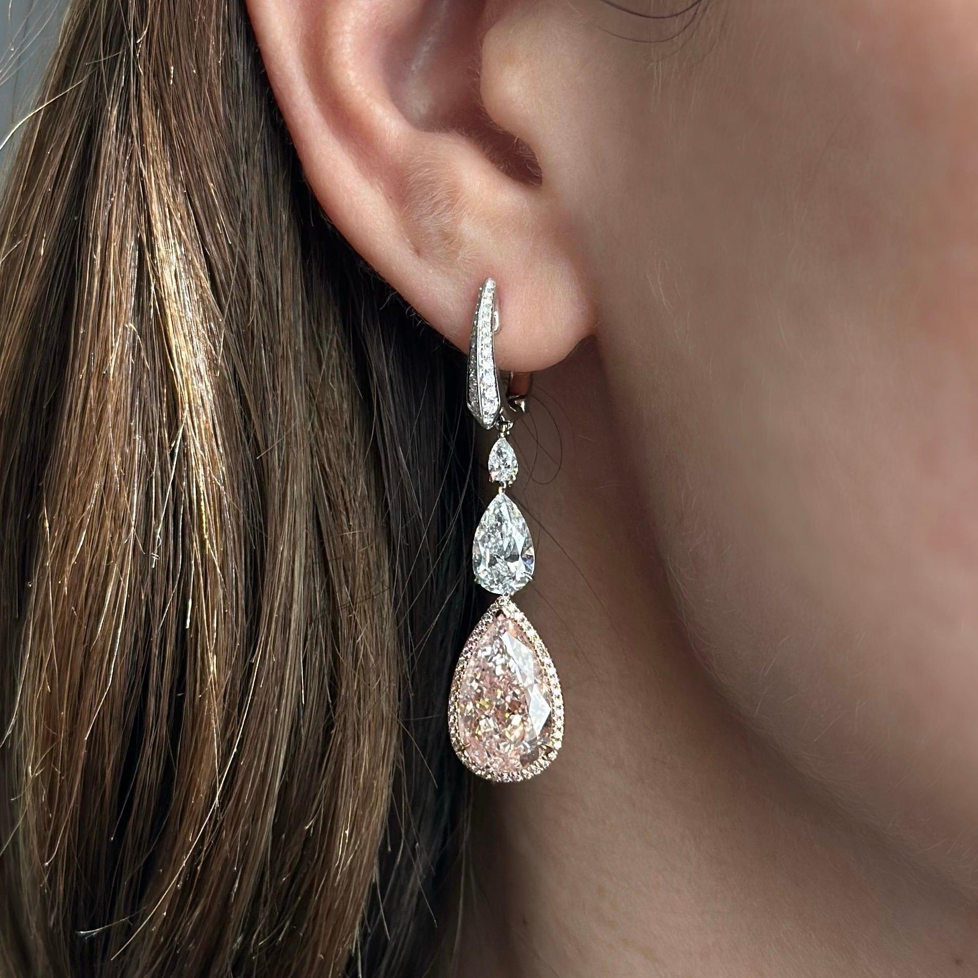 GIA certified 5.01 cts light pink pear shape diamond VS2 clarity and 5.02 cts light pink diamond, VVS1 clarity set in a pave set halo with natural pink diamonds totaling 0.22 cts. 
Pink Diamonds hanging off two GIA certified white pear shape
