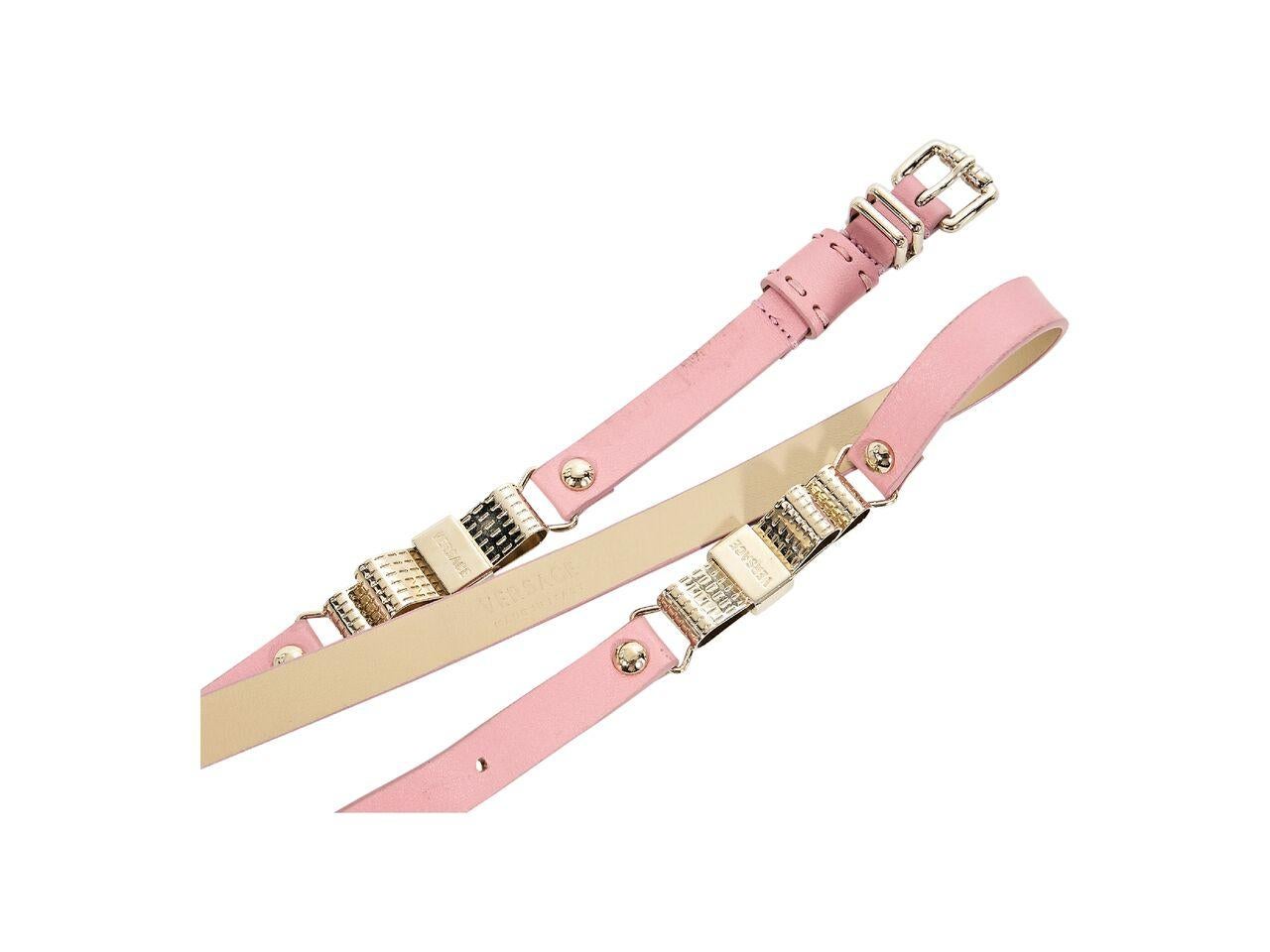 Product details:  Light pink skinny leather belt by Versace.  Accented with two bow charms.  Adjustable buckle closure.  Goldtone hardware.  36.5