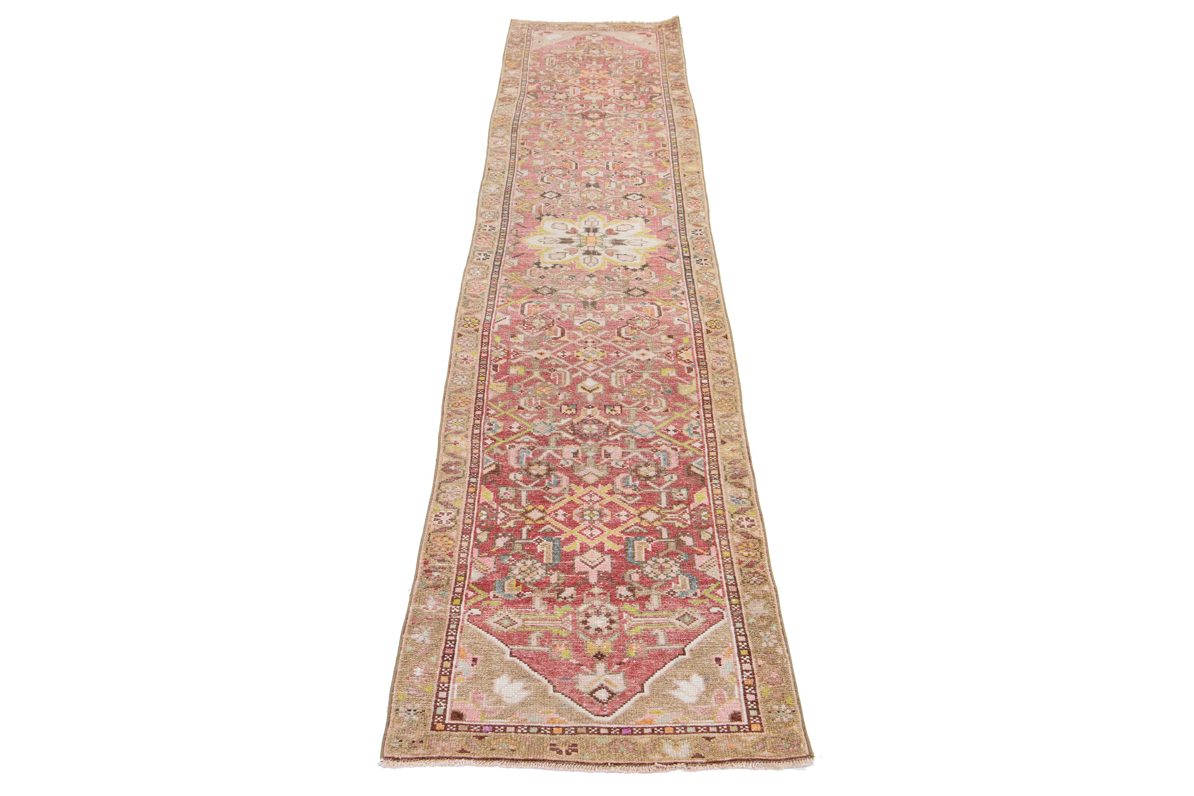 This Persian Heriz wool rug showcases an exquisite traditional floral medallion design with striking multicolor accents against a light pink background. 

This rug measures 2' x 9'6