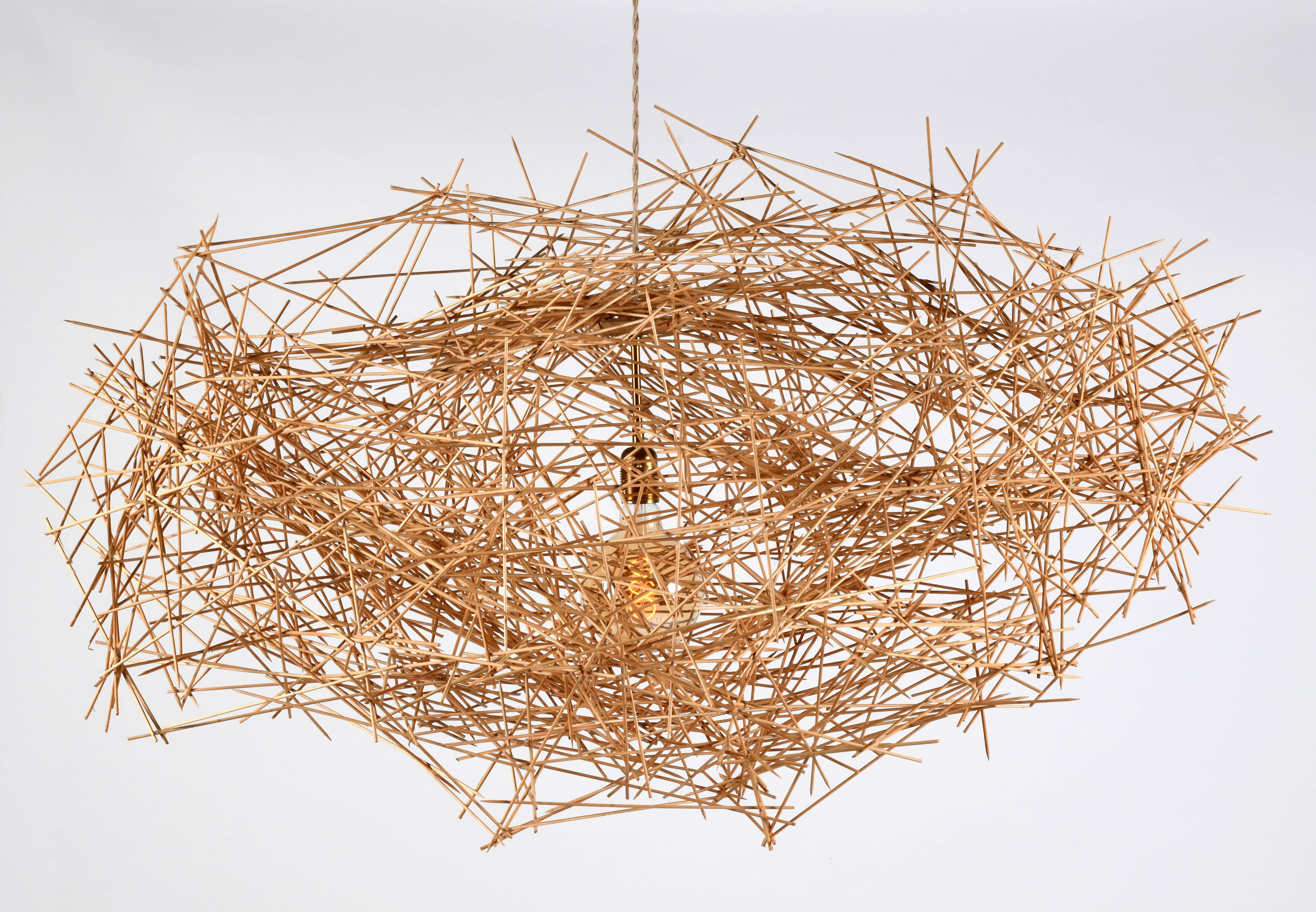 Une sculpture lumineuse suspendue au plafond de l'artiste française Véra Rybaltchenko. Cette pièce unique est entièrement réalisée à la main à l'aide de centaines de tiges de bois collées les unes aux autres.  Le titre générique de ces sculptures