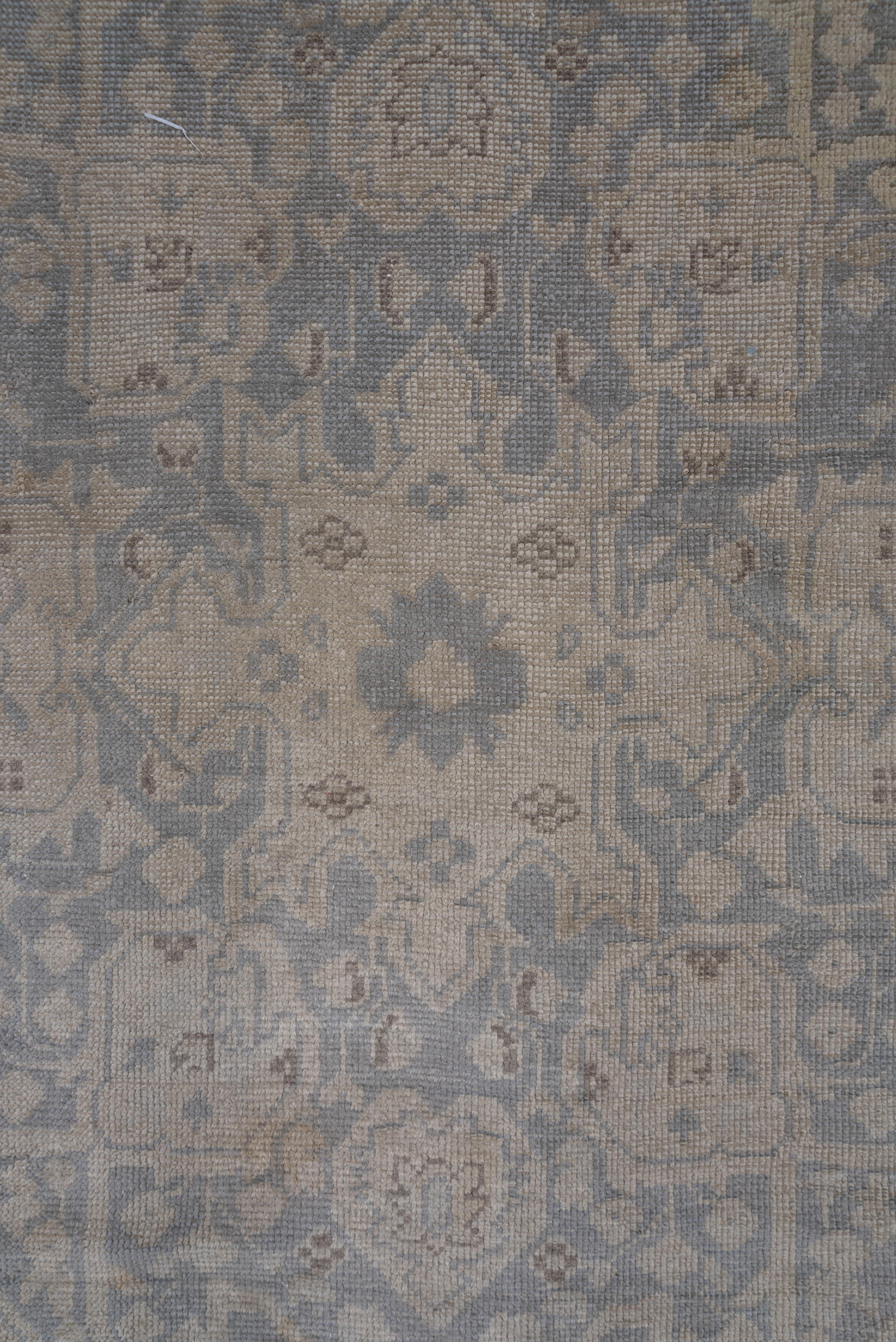 This light colored western Turkish town carpet features a beige open field with a large, slightly scalloped lozenge medallion and arabesque defined corners. The main border shows lollipop flowers, right-angle vines and sketchy turtle palmettes.