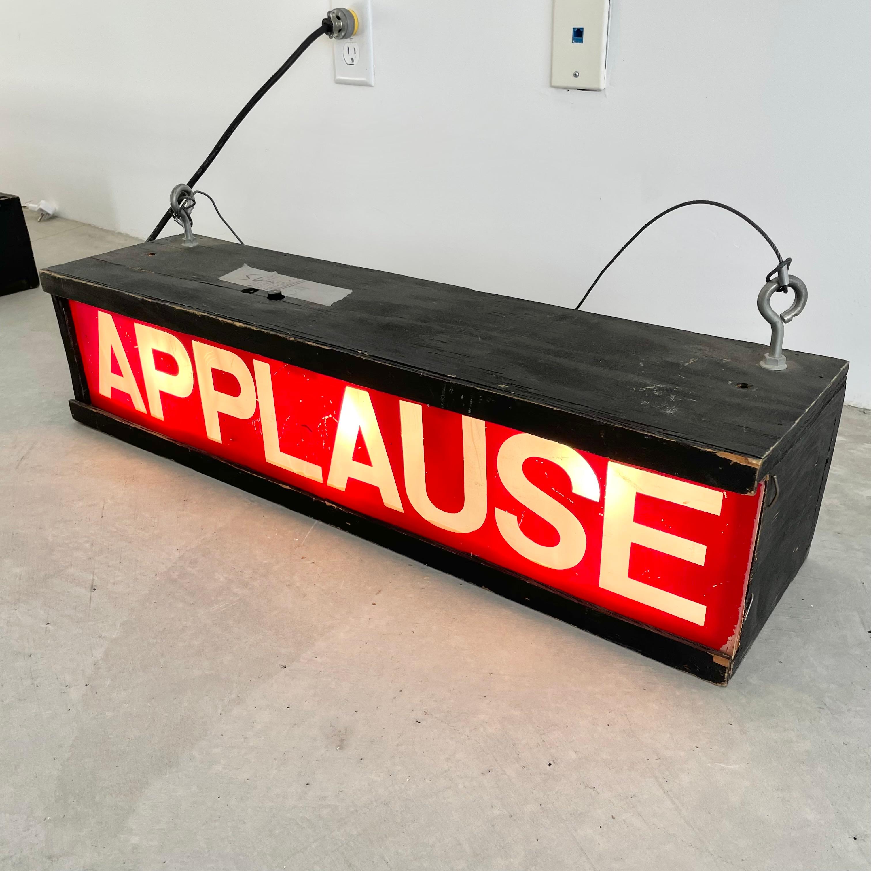 Vintage Los Angeles film studio sign. 2.5 foot long wooden light box painted in a matte black with red and clear acrylic APPLAUSE sign. Fluorescent light inside. Used in a live studio audience studio, with sticker on the back labeling this sign East