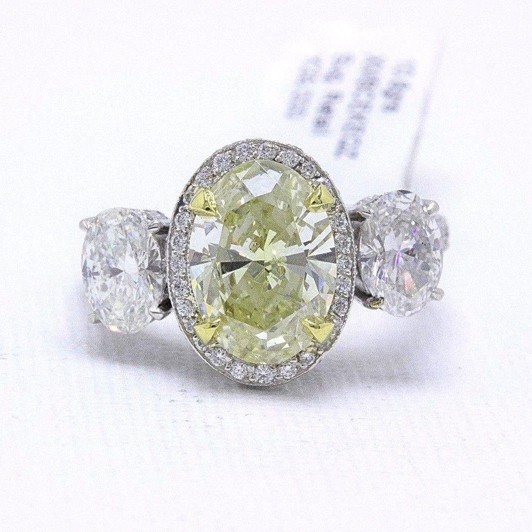 DIAMOND ENGAGEMENT RING
Style:  Three Stone Pave with Milgrain Band
Metal:  Platinum
Size:  6.5   
Total Carat Weight:  6.44 TCW
Center Diamond Shape:  Oval Diamond 3.01 CTS
Diamond Color & Clarity:  Light Yellow / SI2
Side Stones:  2 Oval Diamonds