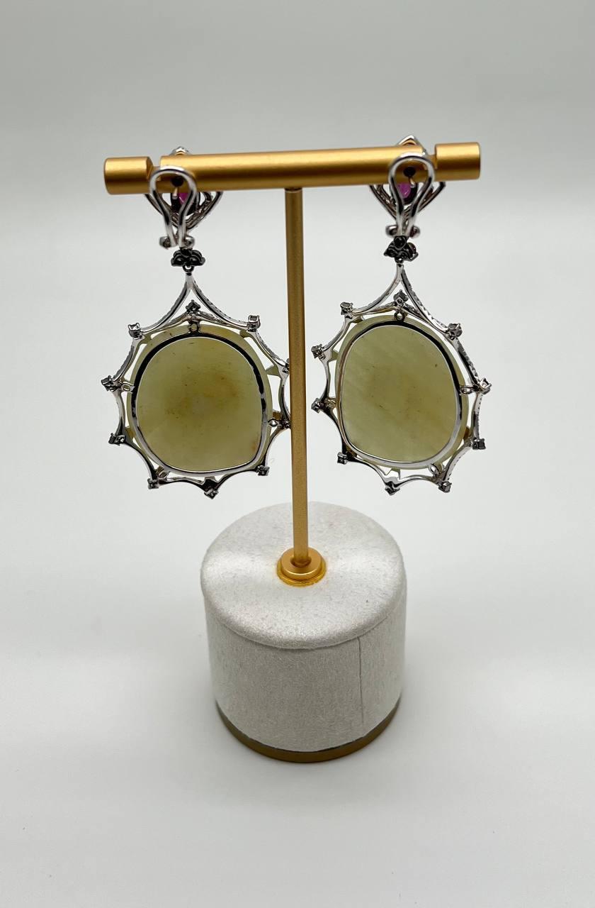 Featuring large, translucent light yellow sapphire slices encased in intricate 14K white gold settings, these earrings captivate with their unique design. Each earring is adorned with a vibrant rhodolite garnets at the top, adding a striking