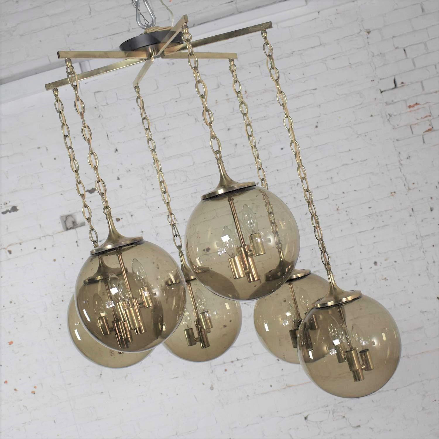 Incredible Lightcraft of California Mid-Century Modern black and brass chandelier or ceiling light with 6 cascading smoke glass orb shaped globes of equal size and brass star canopy. It is in fabulous vintage condition. The brass has been cleaned