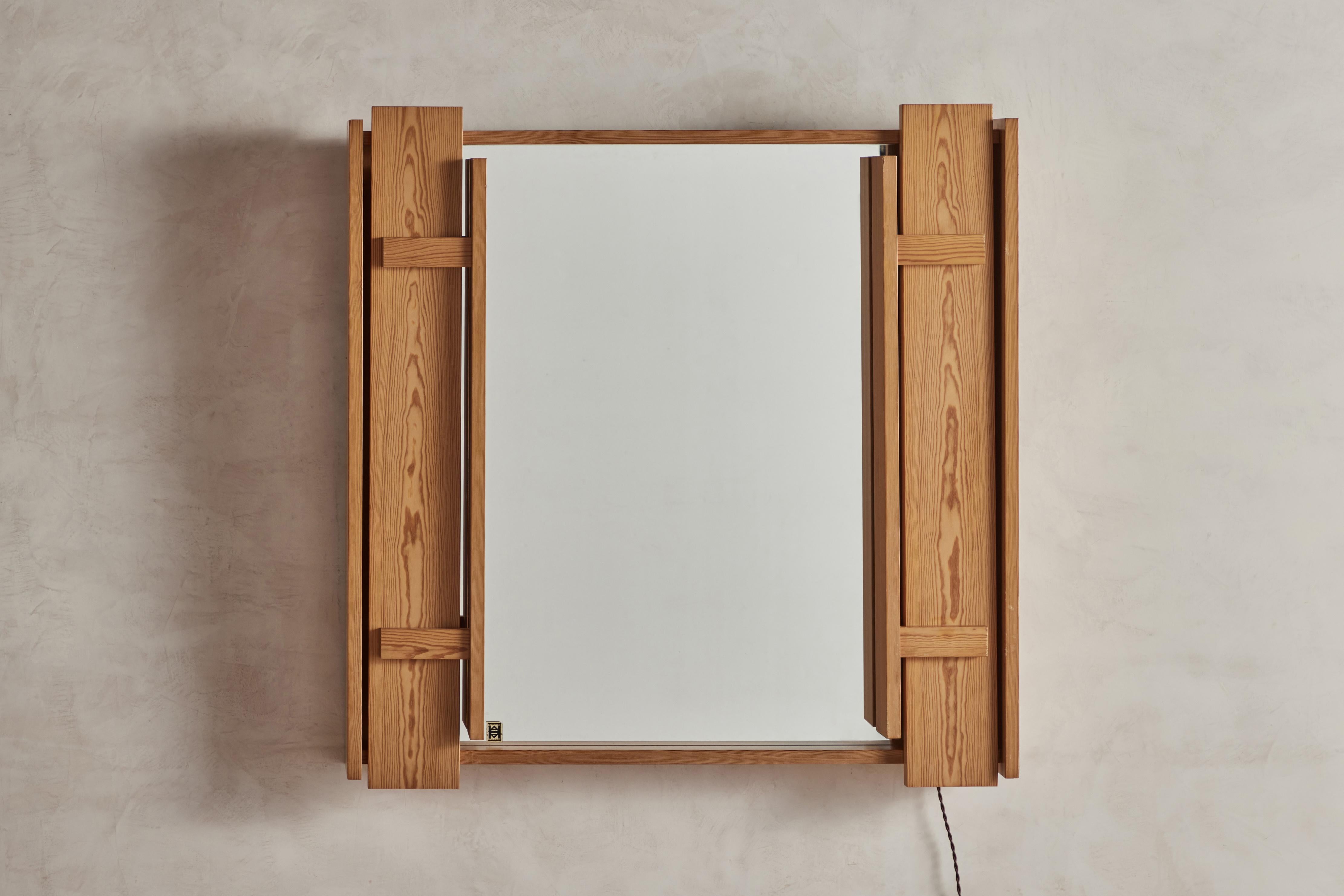 Mid-century lighted mirror by Holsten & Asgard, Norway circa 1960. Two lights behind a sculptural wood frame, flank this unique wall mirror. Electrical wiring is new with a cloth covered twist cord and power switch for plug installation. (Bulb Info: