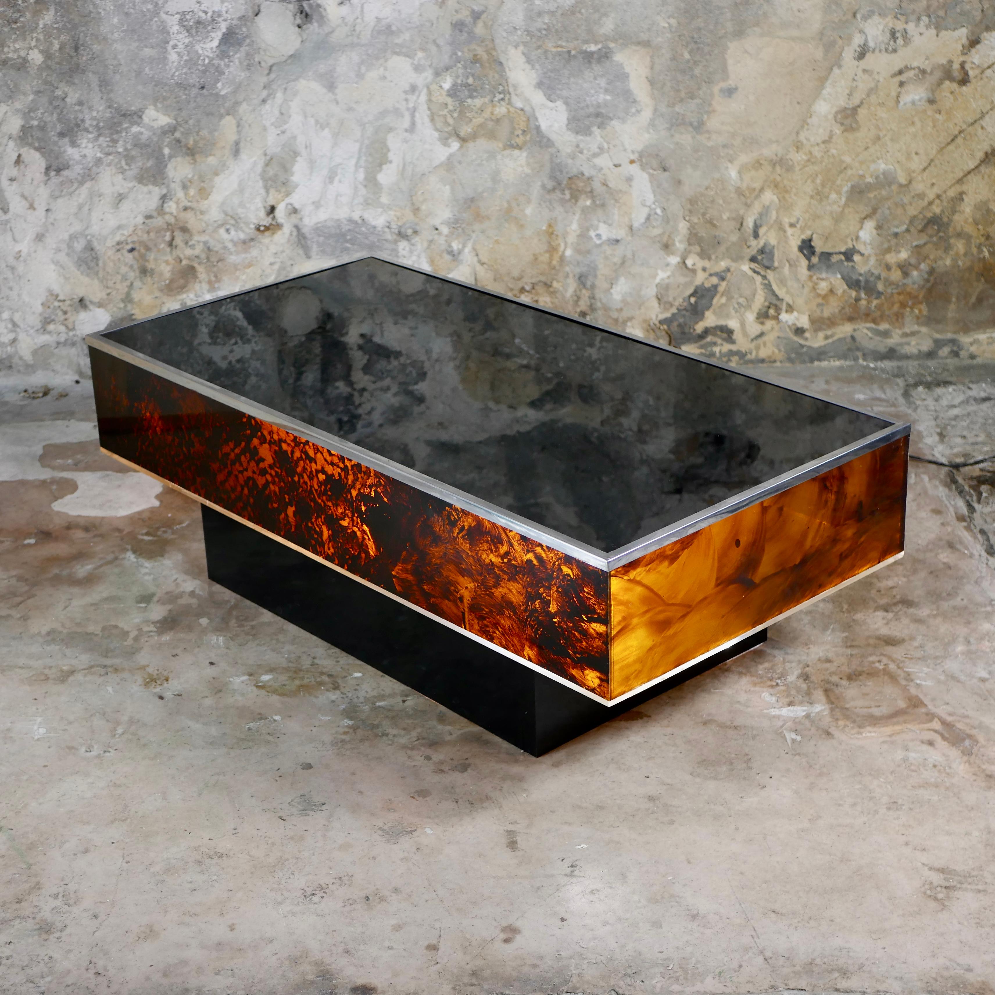 Lighted up coffee table, in faux tortoise lucite, in the style of Willy Rizzo, Dior Homme or Jean-Claude Mahey, made in Italy in the 1970s.
Faux tortoise lucite and black glass top, with a chromed steel rim. Electrified, with 2 bulbs under the