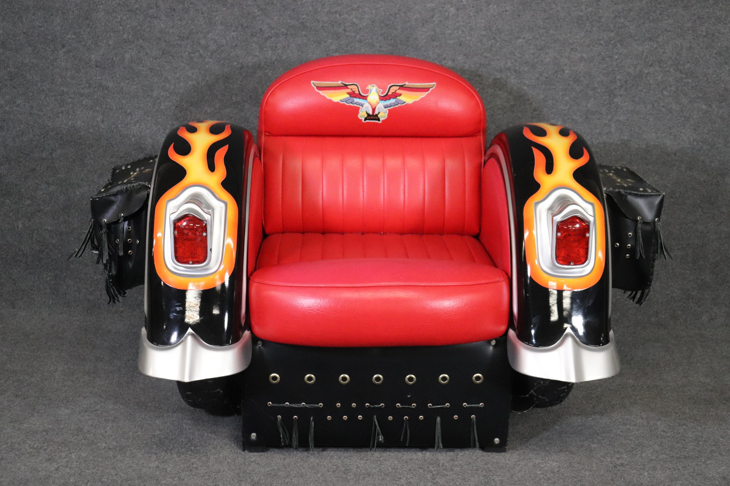 This is a fantastic and fun design for a club chair. The chair lights up and is very good condition as its not very old. The chair is fitted with a red faux leather seat and designed to look like a vintage Indian or Harley motorcycle and is signed