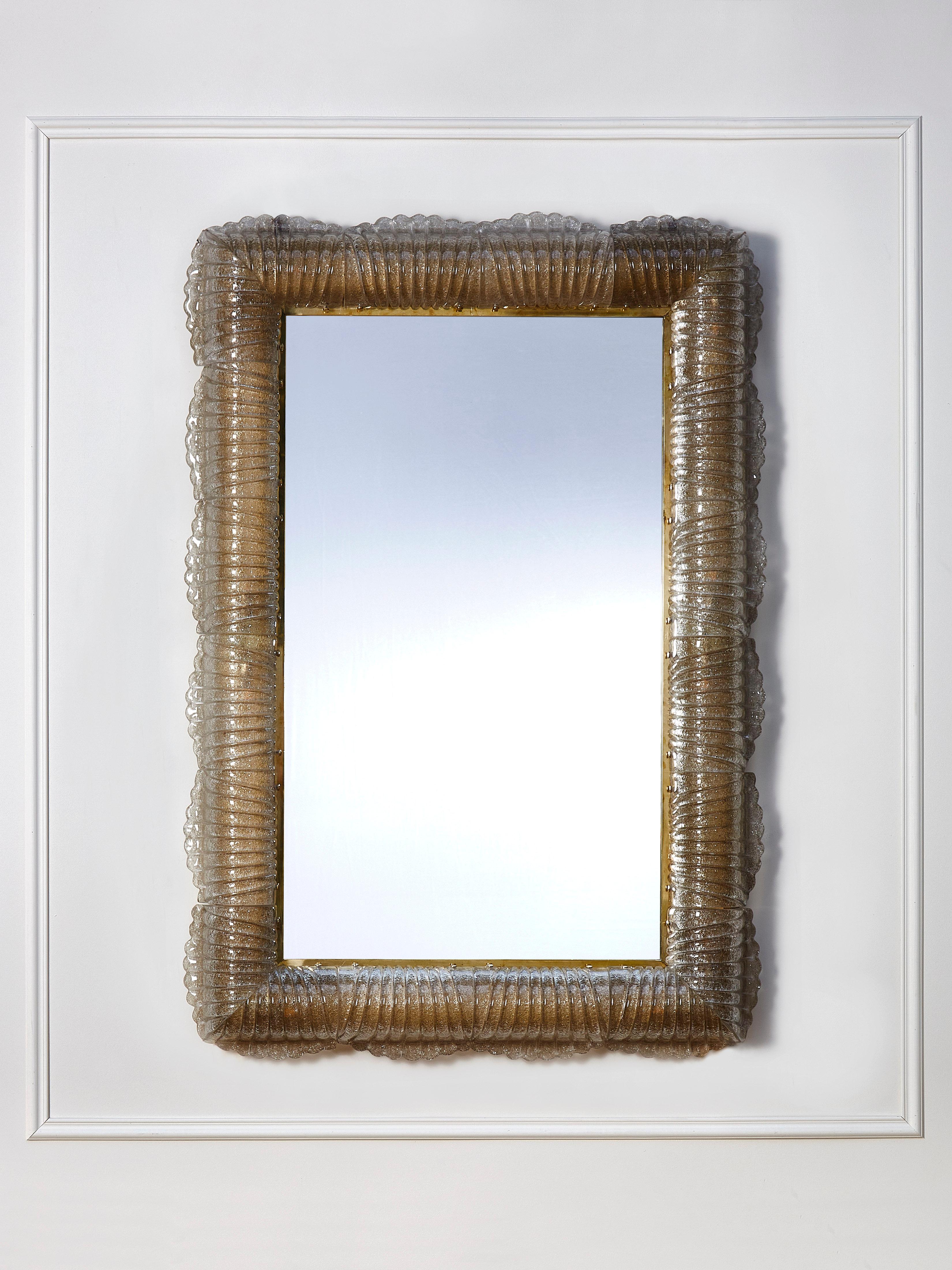 Beautiful pair of mirrors in brass and sculpted, lightened Murano glass frame. 
E14 light bulbs.
Creation by Studio Glustin.