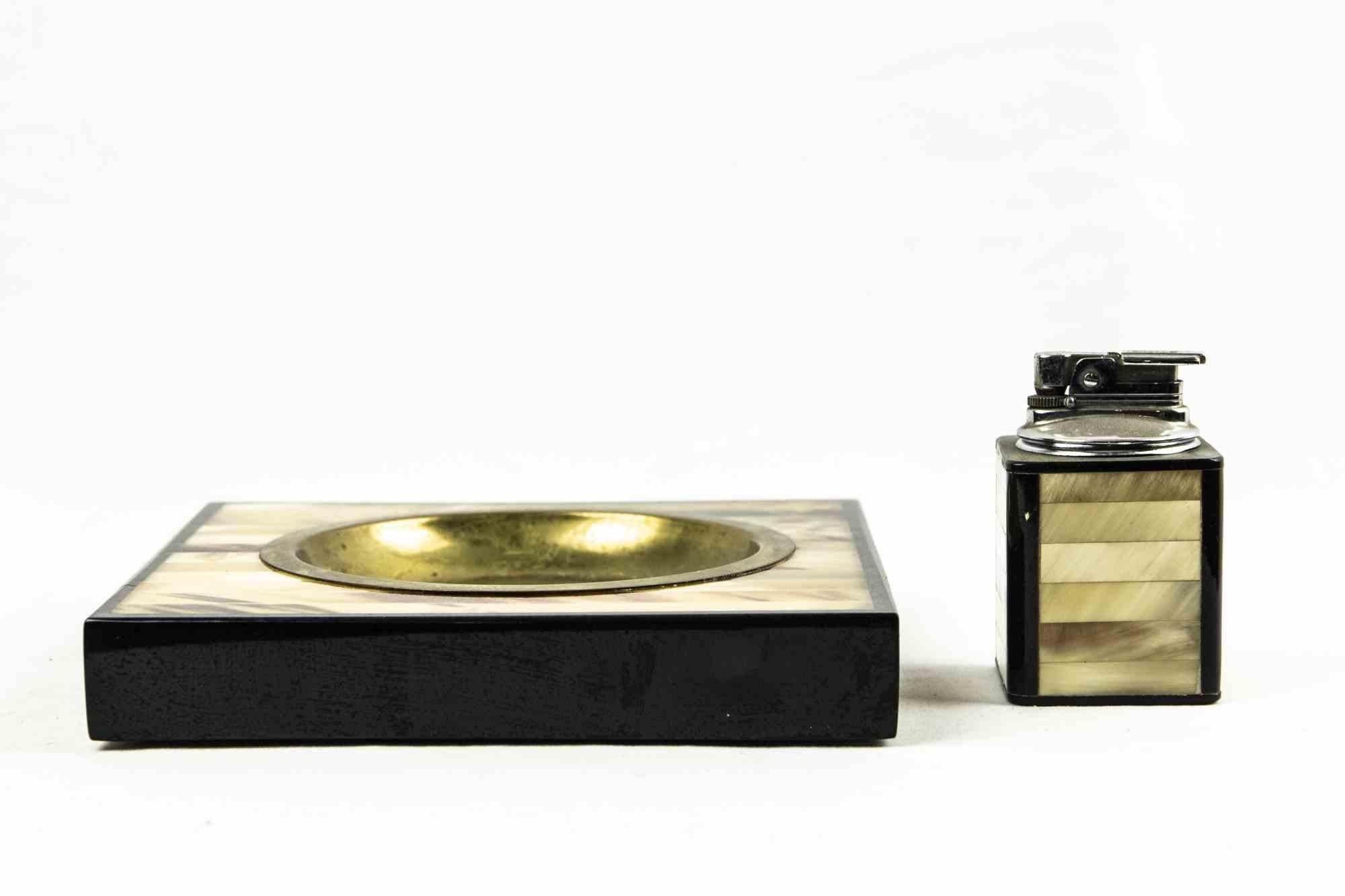 Lighter and ashtrays set is an original decorative object realized in the 1970s.

An elegant set composed by an ashtray and a lighter in brass and metal, with the surface reproducing a mother-of-pearl effect.

Good conditions except of signs due