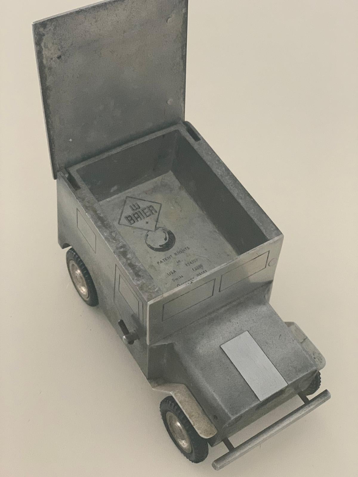 Table lighter, from 1948, in the form of a jeep. Made by the company Walter Baier made of aluminum. At the touch of a button, the lid opens and ignites the lighter. The lighter is in a good condition, used according to the age. The jumping mechanism