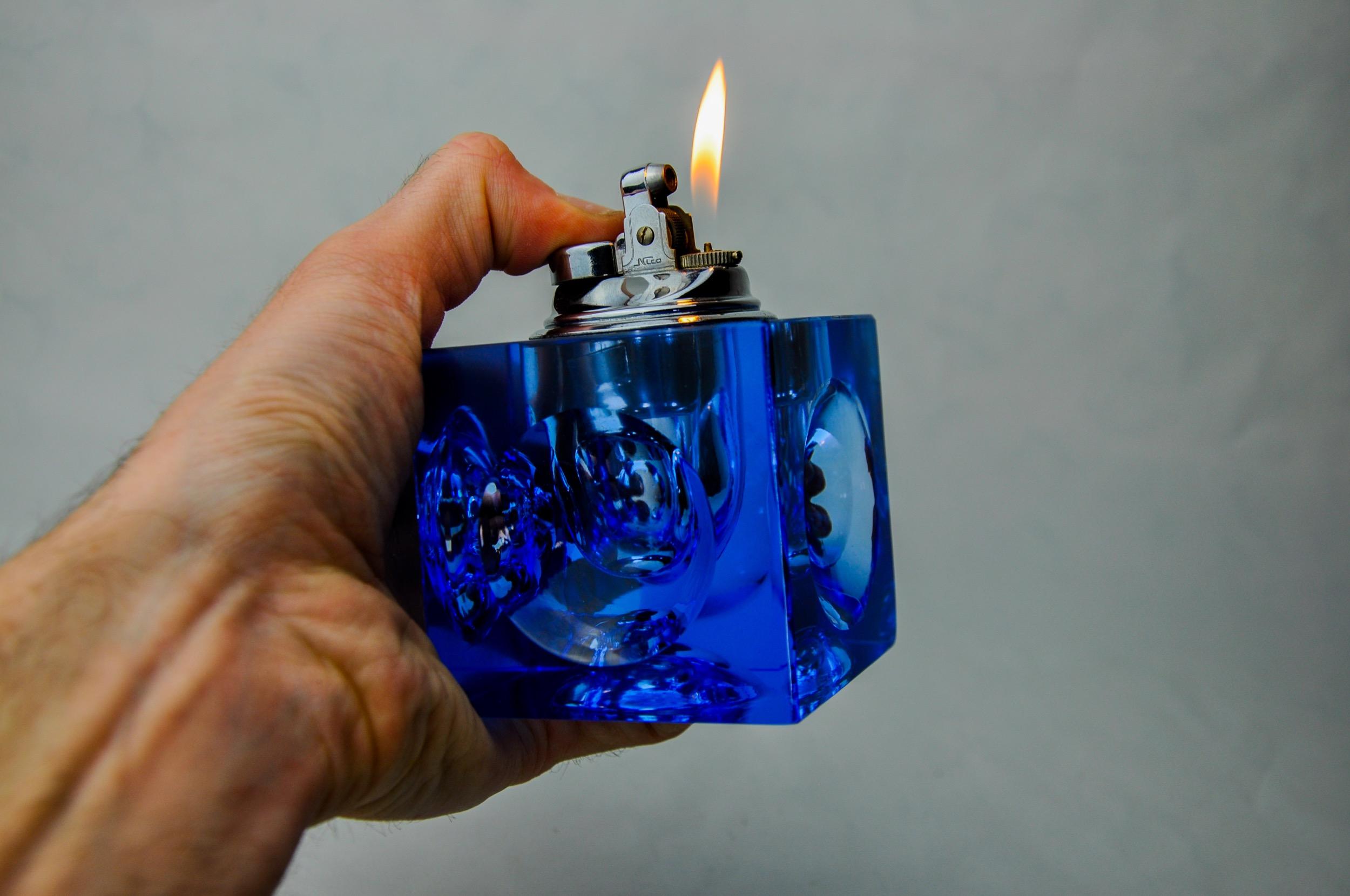 Superb magnifying lighter designed and produced by Antonio Imperatore in Italy in the 1970s. Blue Murano glass lighter with a magnifying effect on its facets, handcrafted by Venetian master glassmakers. Decorative object that will bring a real