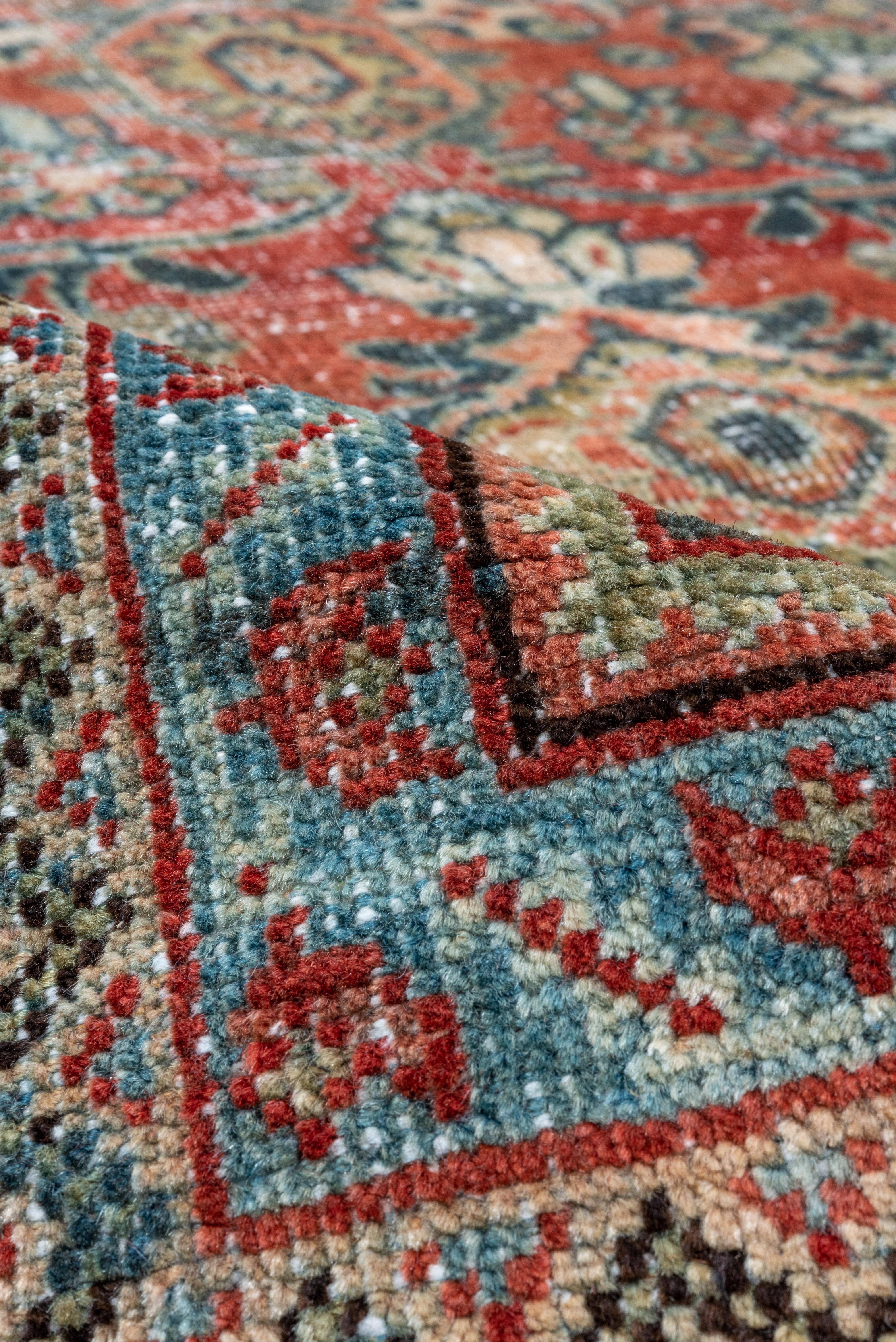 The rust-red field displays a characteristically unusual all-over Mahal pattern of oblique long leaves, tabbed octagons, palmettes, cruciforms with petal palmette fiials and other unusual motives. Accents in shades of blue teal and green. Sapphire