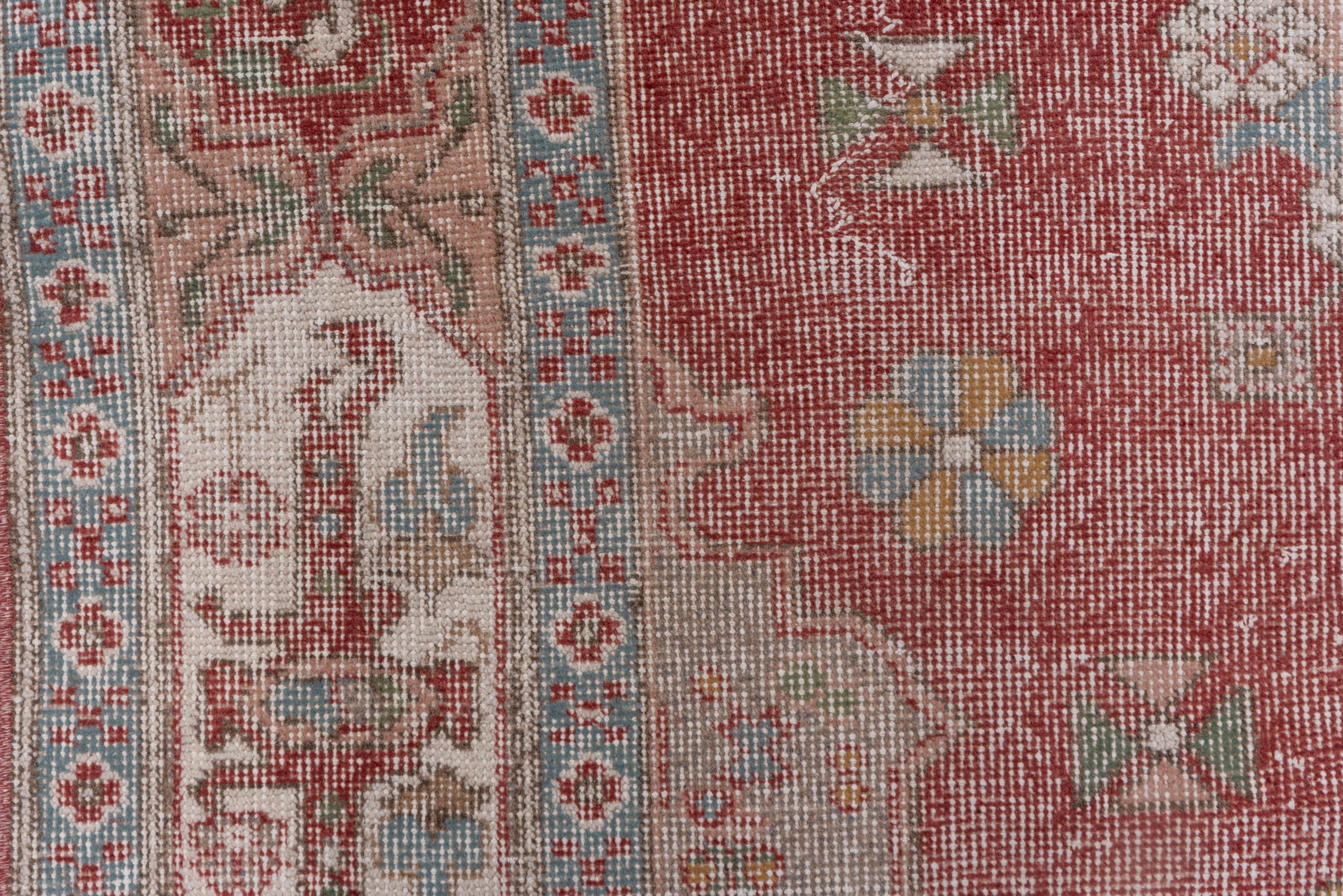 The soft red field supports a double rosette wreath lozenge medallion in the Bergama Turkish style, corners anchored by rosettes, and a 