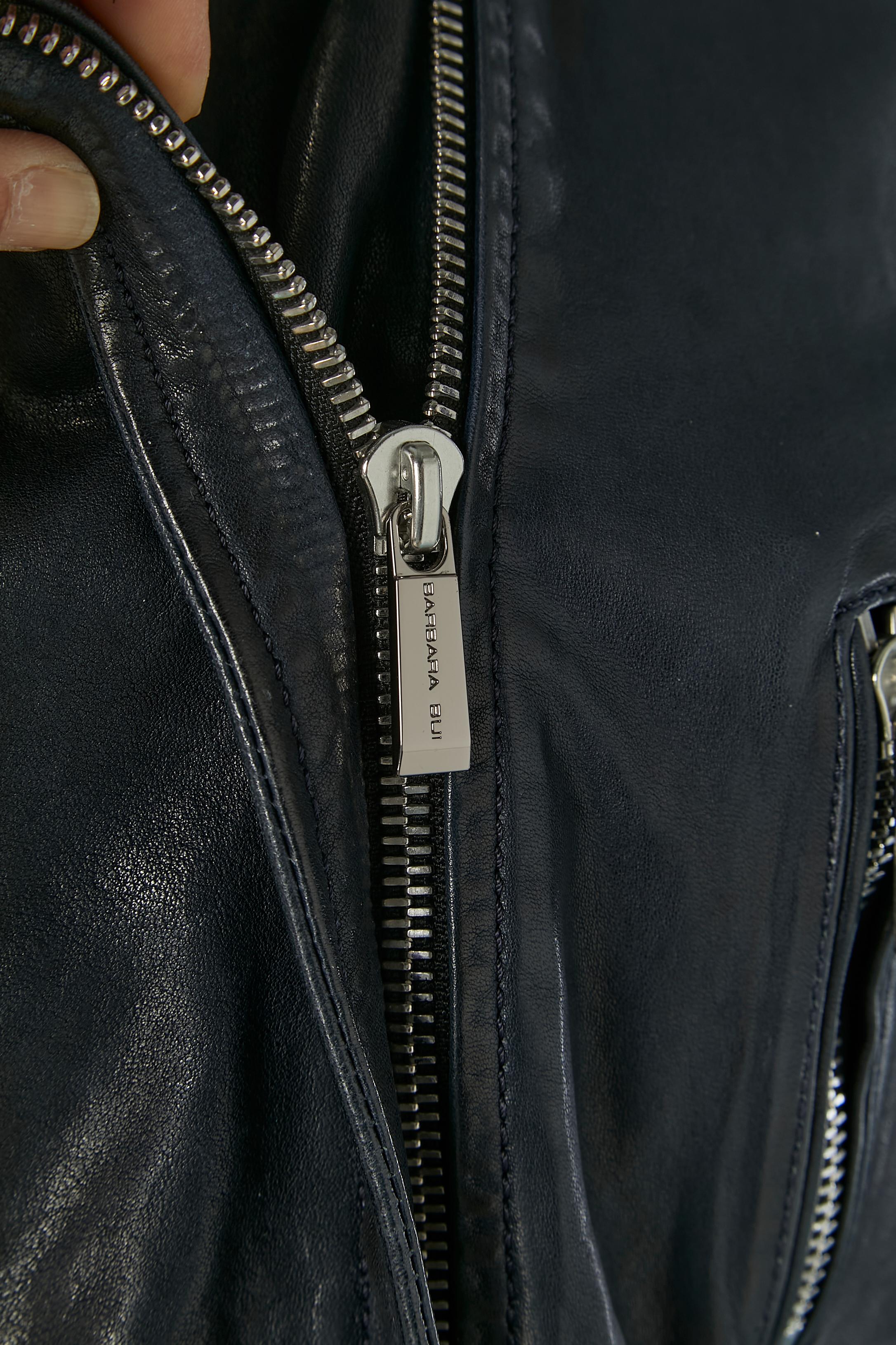 Giacca biker in pelle nera leggermente imbottita con lacci in pelle sul lato, sulla schiena e sulle maniche.  Fodera in acetato all'interno del corpo e fodera in rayon all'interno delle maniche. Composizione del pad: 100% poliestere. 
Chiusura a zip