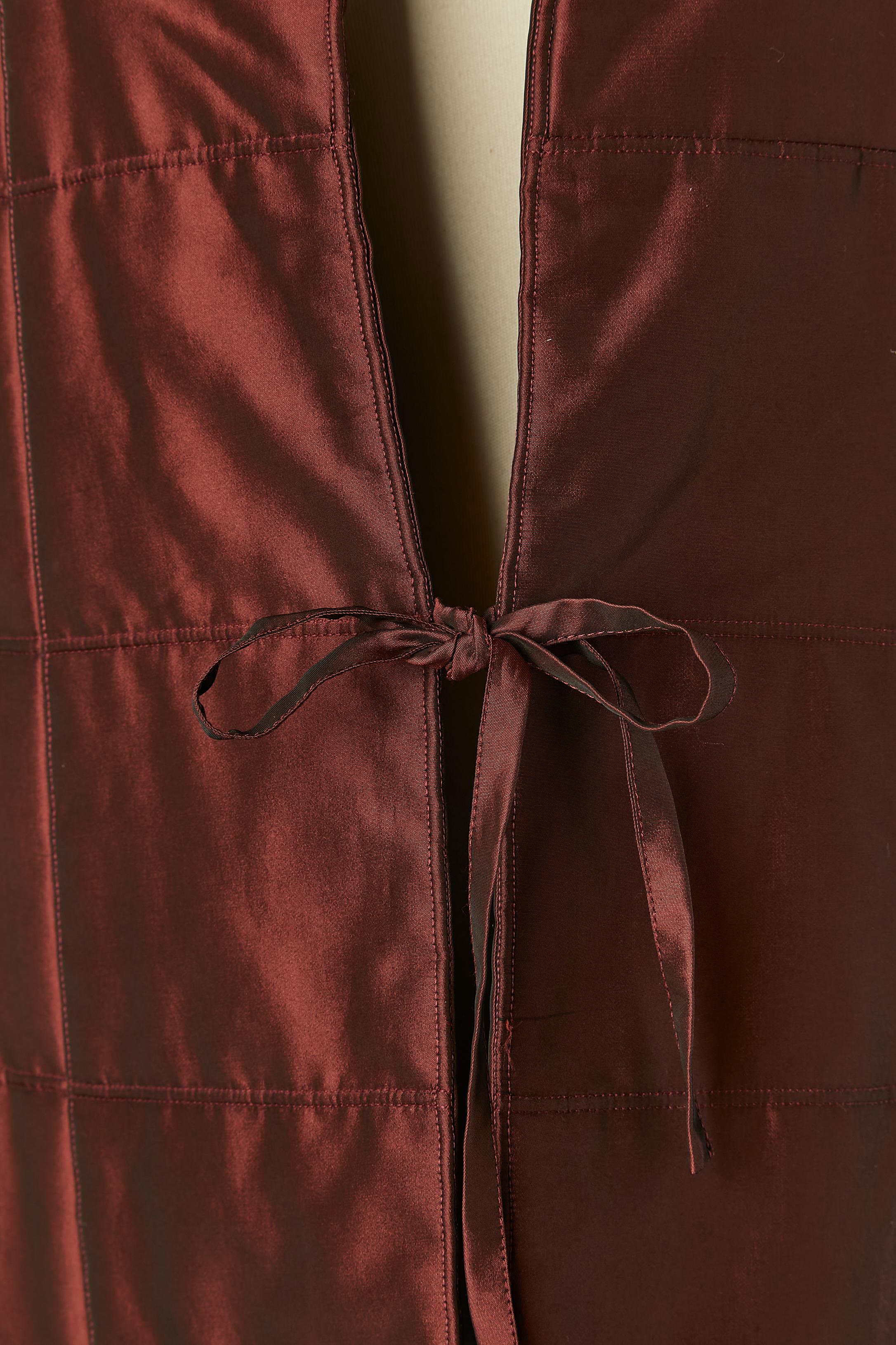 Manteau de soirée bordeaux légèrement paddé.
Composition du tissu : 55% polyester, 35% acétate, 10% nylon, doublure en soie.
Épaulière fine. Fermeture par un nœud sur le milieu du devant. Poche sur les deux côtés avec fermeture à glissière