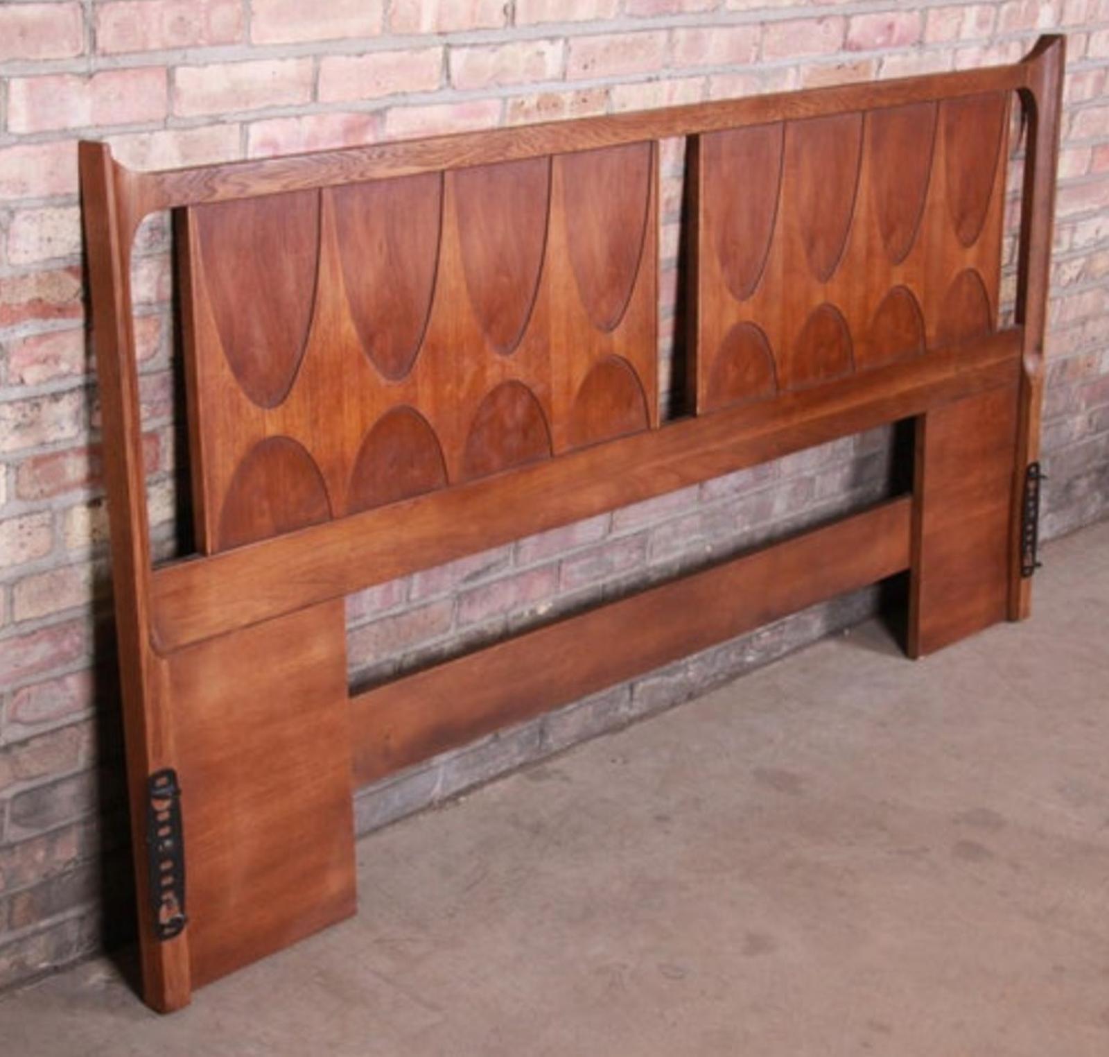 This fantastic headboard was built in the 1970s by high-end manufacturer Broyhill for their Brasilia line of furntiure. Since then, the Brasilia line has become more desirable, and original sets are difficult to come by. Featuring walnut