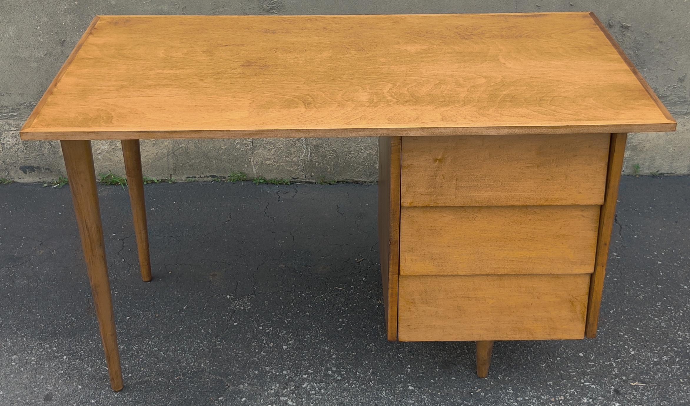This rare desk was designed in the 1950s by Florence Knoll with a simplistic profile that has proven to be timeless! Of solid maple construction, it features tapered dowel legs and a single pedestal with three large drawers, topped by a neatly