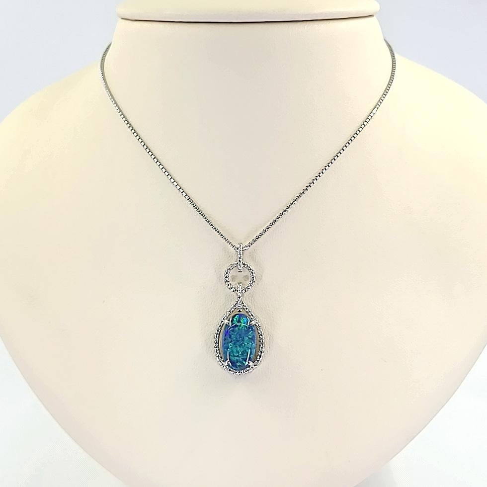 Stunning 18 Karat White Gold Pendant Necklace Featuring A 3.54 Carat Oval Lightning Ridge Opal with Gorgeous Green and Blue Play of Color. 0.27 Carat Total Weight Round Brilliant Cut Diamonds of VS Clarity and G/H Color Surround the Opal. Adjustable