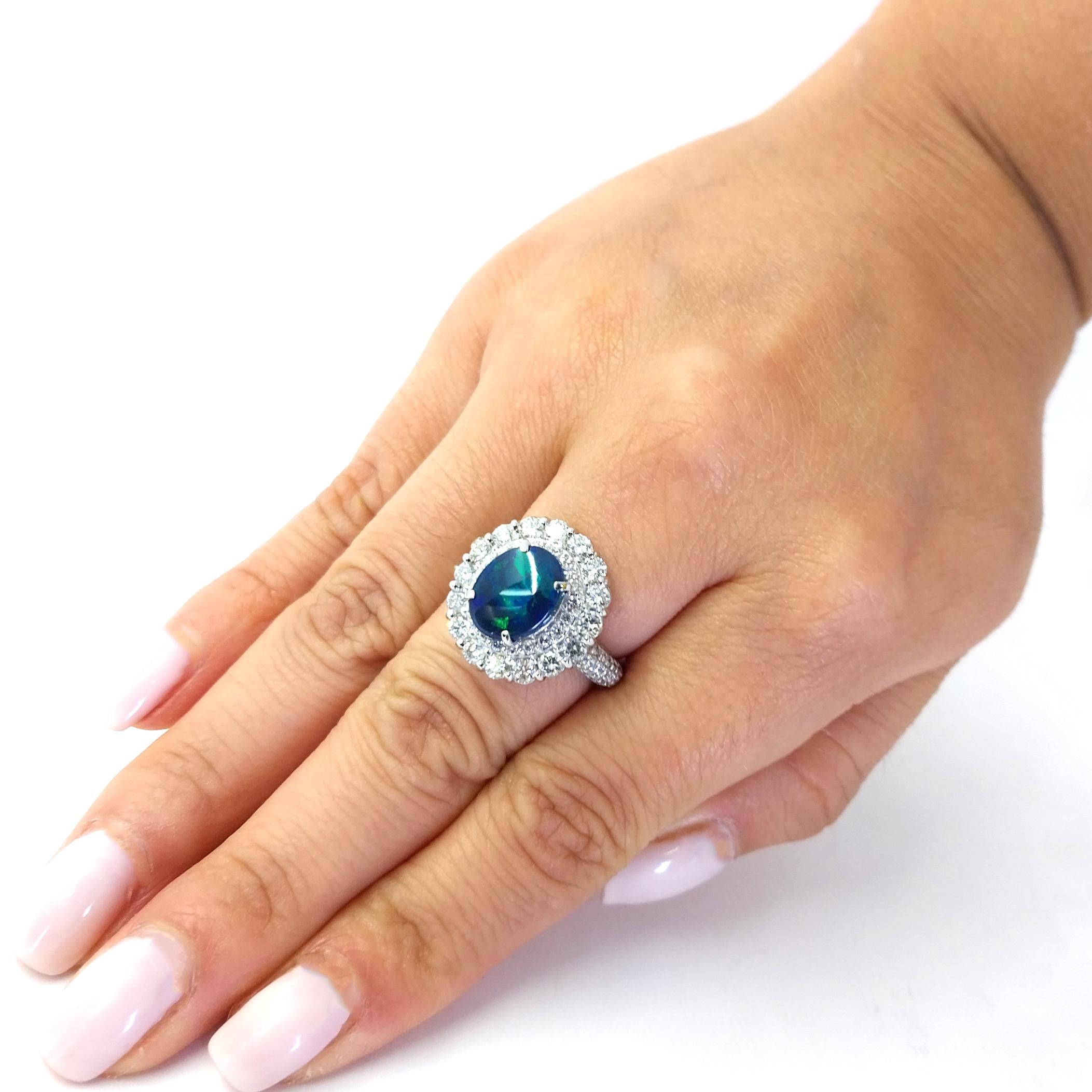Platinum Lightning Ridge Opal Ring Featuring A 2.30 Carat Oval Australian Opal with Beautiful Blue and Green Play of Color, Accented by 1.10 Carat Total Weight Round Diamonds of SI Clarity and G/H Color. Finger Size 5.75. Purchase Includes One