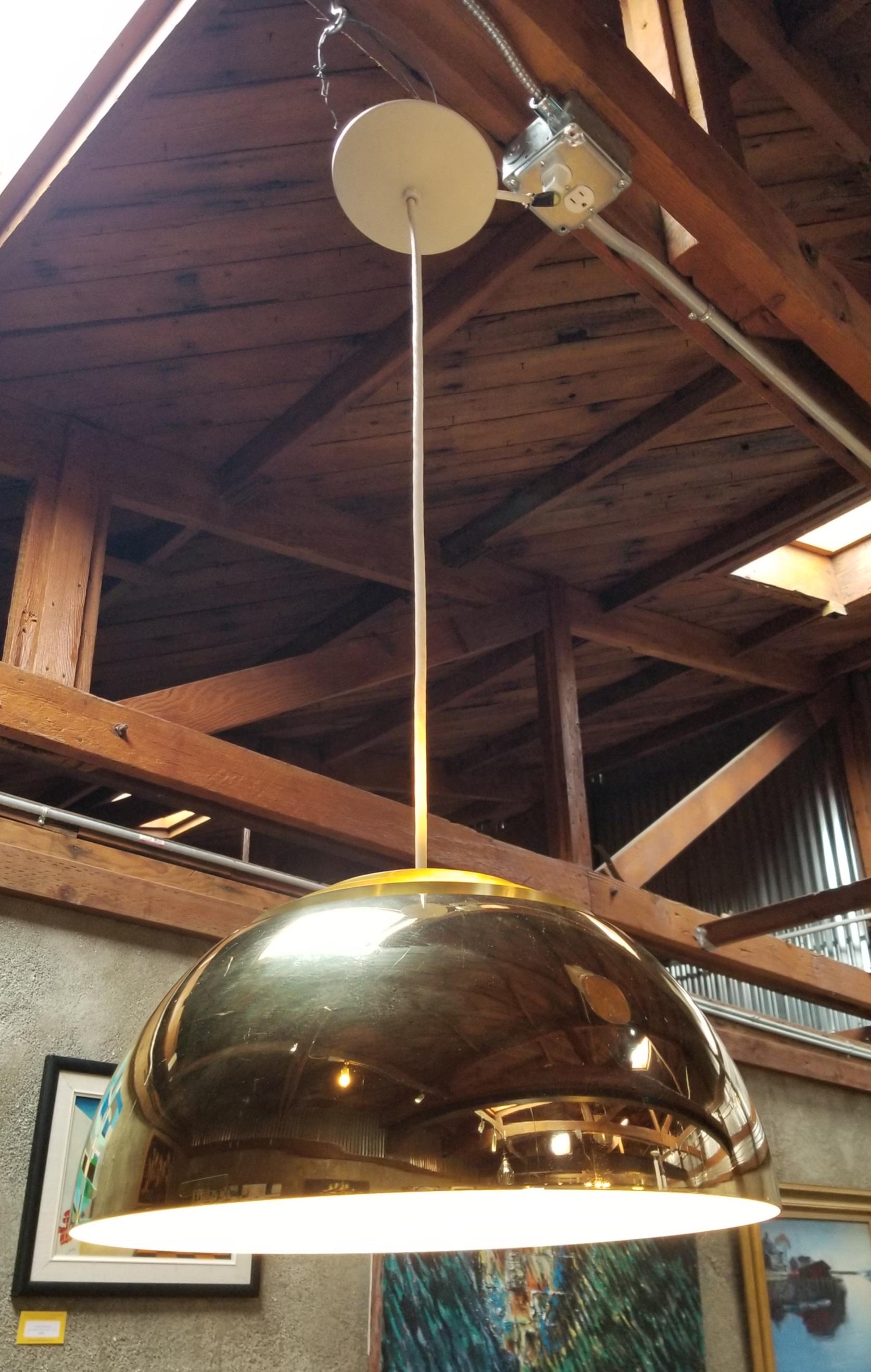 A polished brass pendant chandelier by Lightolier. Designed with 5 concentric, brushed brass louvers over a polished brass metal domed shade. Concentric bands allow filtered upward light. Retains Lightolier paper label. Can use with a 150 watt