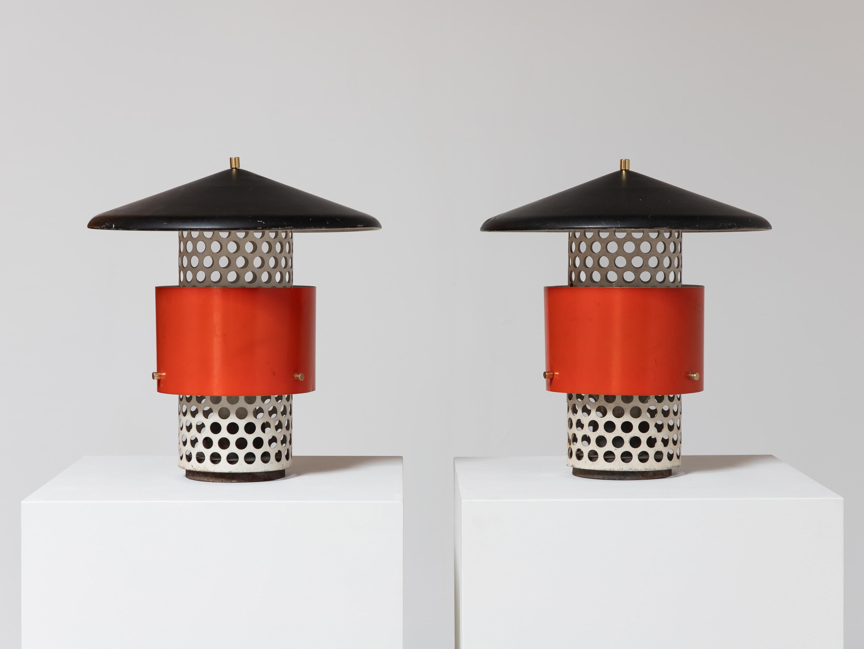A scarce pair of Lytescape outdoor lamps, often attributed to Gino Sarfratti, manufactured by Lightolier.  These vintage lamps feature perforated metal bases with a bright vermillion shade, elevated with brass hardware and finials. The lamps are