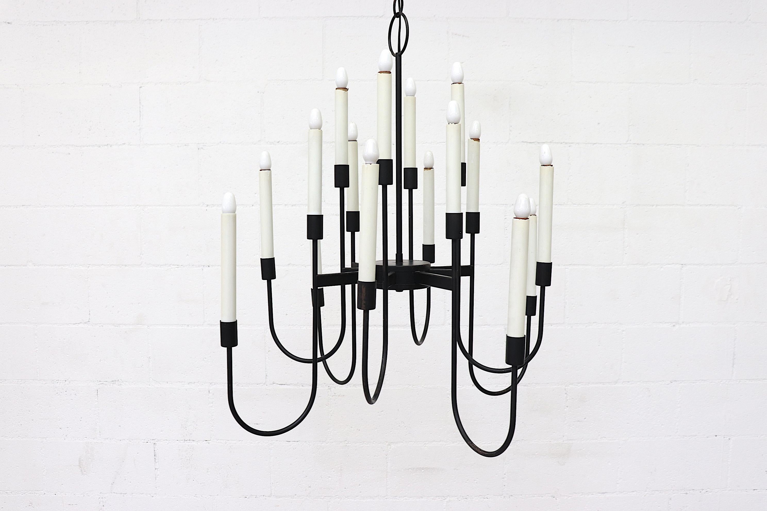 Mid-century black enameled candelabra inspired chandelier by Lightolier with 16 candle stick arms. Traditionally designed and dressed in Classic black and white. In original condition with visible wear and some enamel loss, wear is consistent with