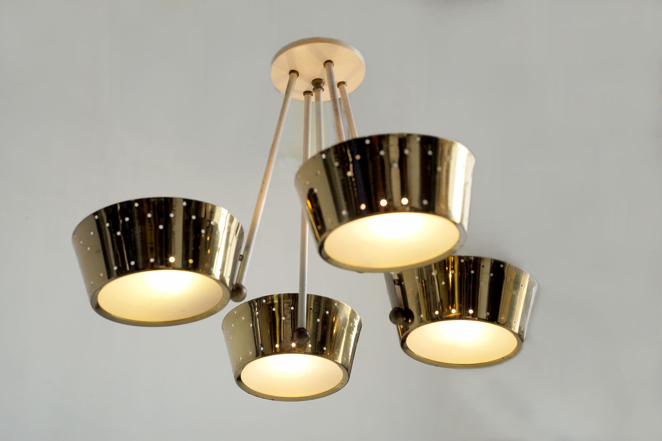 Suspension attributed to Lightolier, in the style of Paavo Tynell, with four polished and perforated brass reflectors, USA 1950. The basin-shaped reflectors receive a frosted glass plate, the structure is white lacquered, enhanced by golden balls.