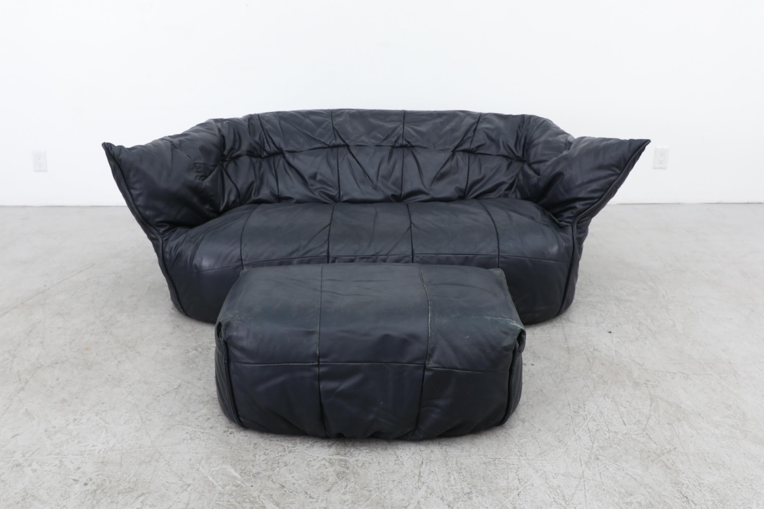 Lignet Roset Brigatin Navy blue leather loveseat and ottoman by Michel Ducaroy for Ligne Roset, 1970's. Eye catching distinct curvature defines the piece's timeless appeal and makes it visually appealing and physically inviting.
This soft form sofa