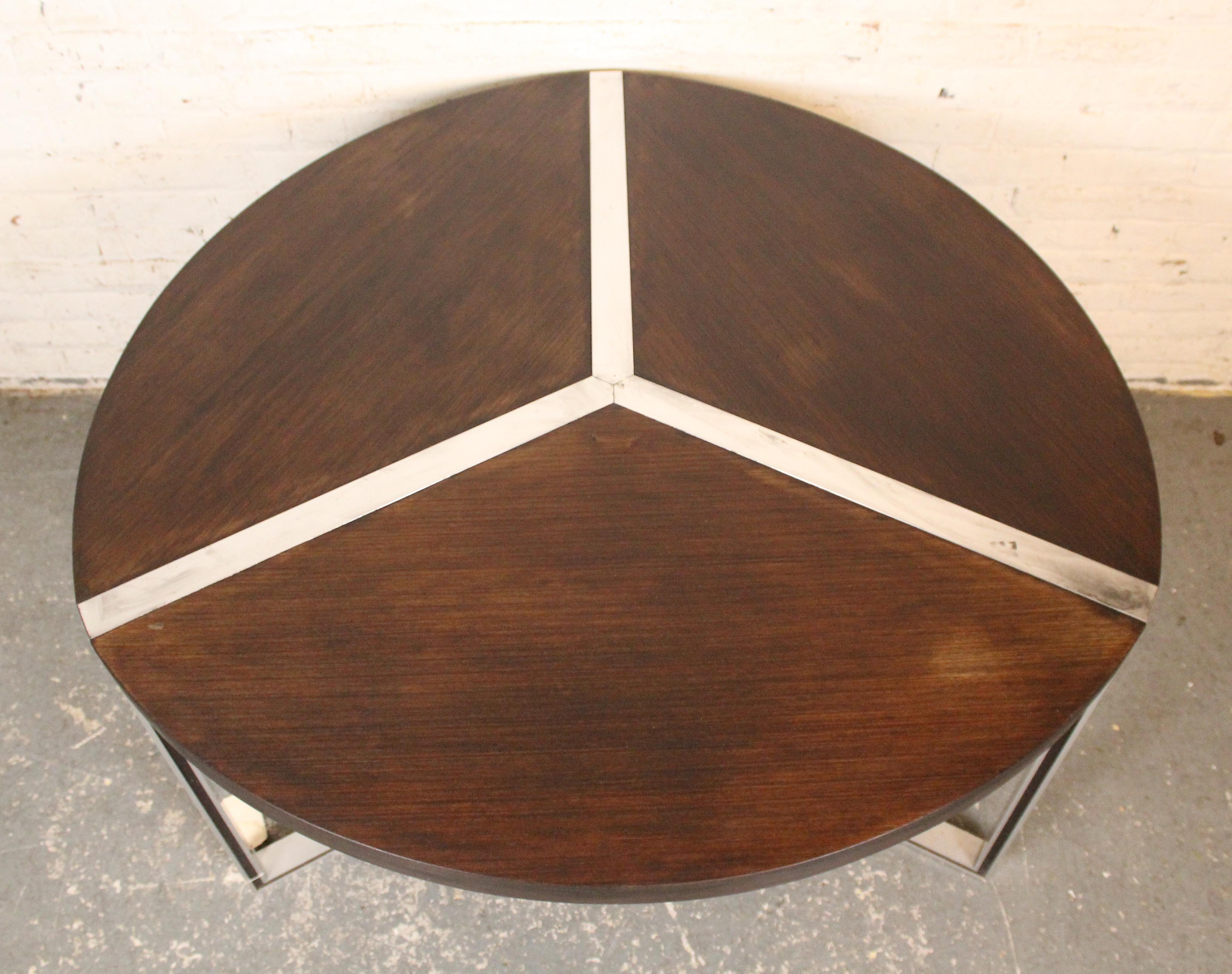 This vintage table designed by Henri Lesetre & Claude Gaillard for Ligne Roset features a modern and simplistic design. Dark mahogany colored wood is offset by the silver colored aluminum frame that intersects the top. The wood is again accented