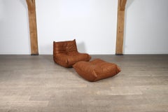 Fauteuil de salon Togo Ligne Roset avec pouf en cuir cognac par Michel Ducaroy