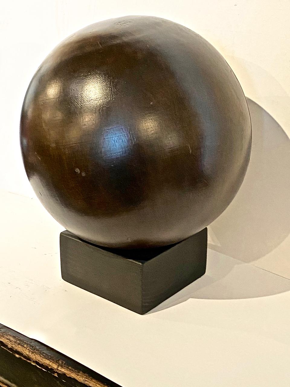 This is an example of an early 20th century Lignum Vitae bowling ball on stand. This ball was not drilled for finger grips, perhaps because of the split shown in the photos. The ball would make a great decorative element for a masculine study or