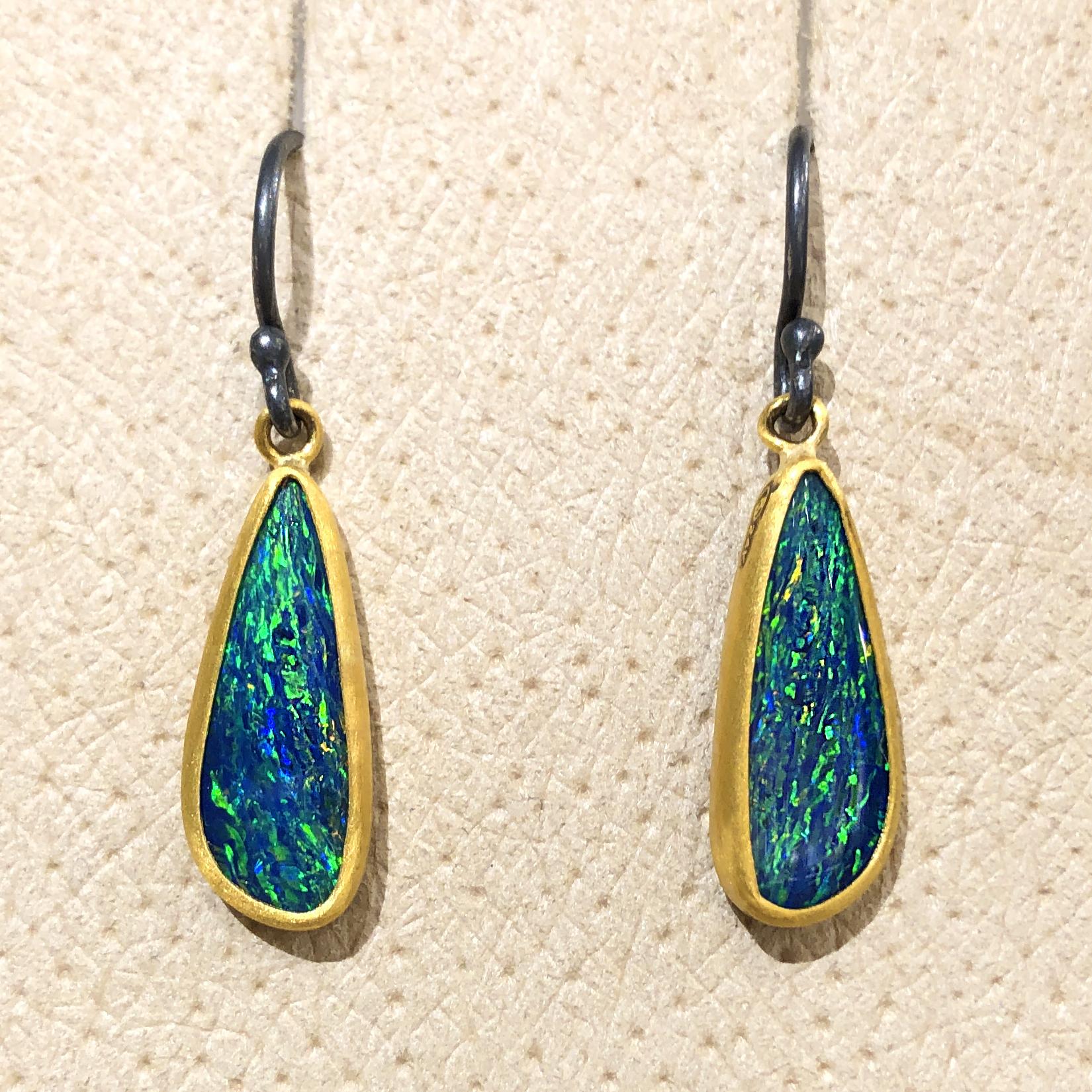 Opal Doublet Dangle Drop Earrings handcrafted by acclaimed jewelry maker Lika Behar featuring a gorgeous matched pair of blue opal doublets with primary electric green flash complemented by oranges and reds, bezel-set in 24k gold and attached to