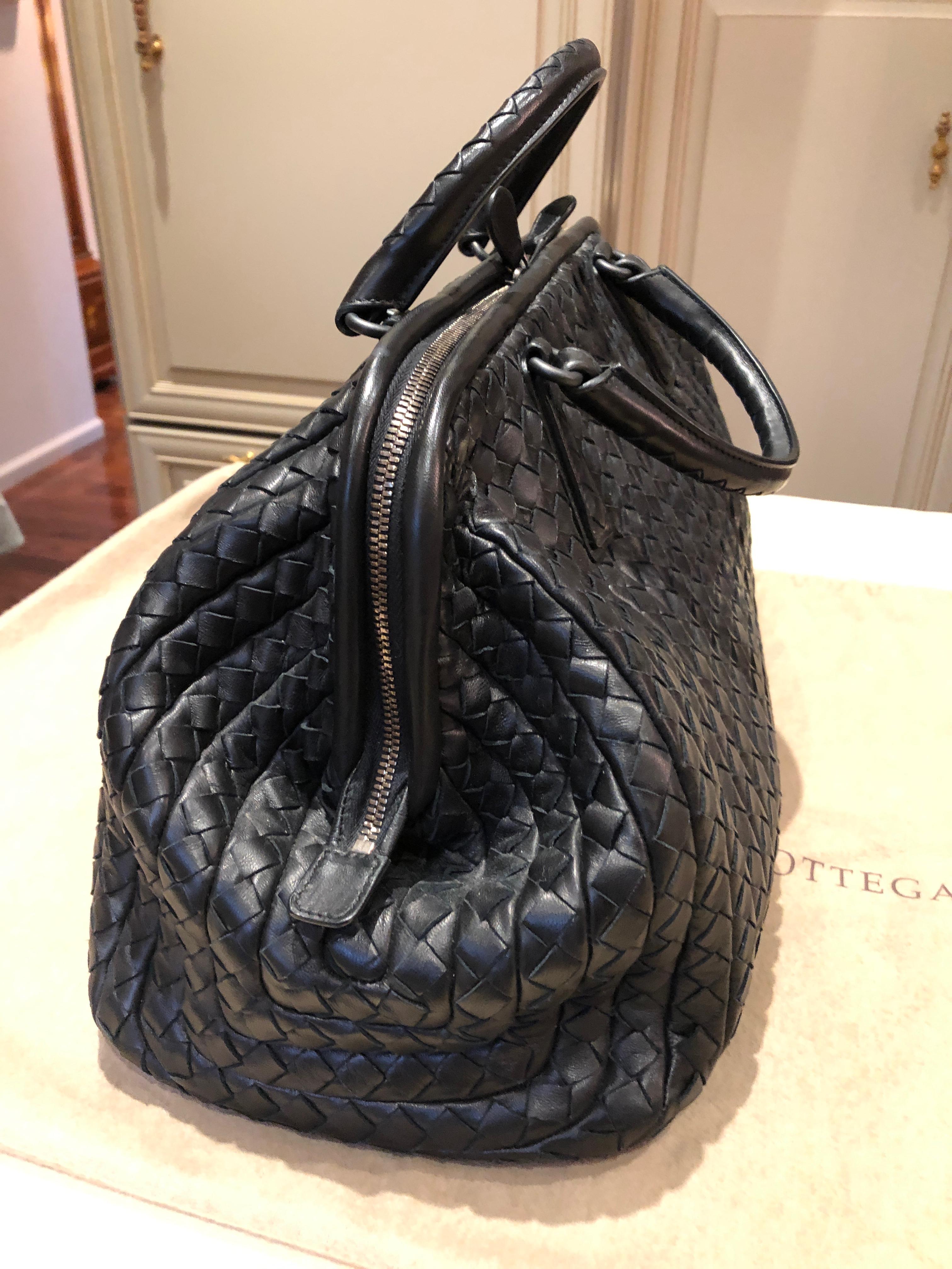 Exceptional black Bottega Veneta new bond satchel crafted of calfskin leather in the Intrecciato signature pattern. The bag features two rolled handles, top zipper closure, and a suede lined interior with small pocket and zippered compartment. Comes