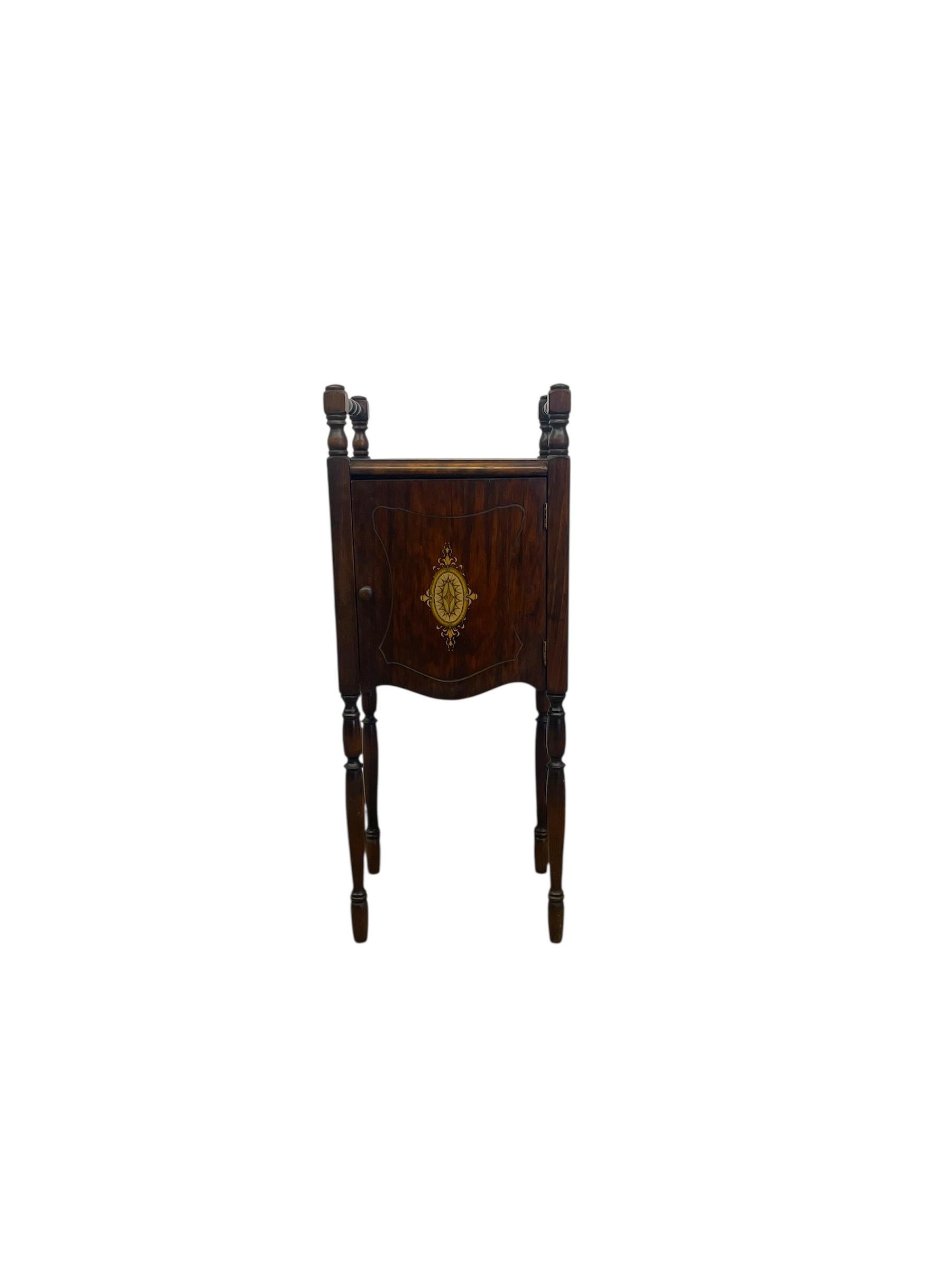 Este armario para fumadores probablemente eduardiano de principios del siglo XX presenta una galería y patas de husillo finamente torneadas, una sola puerta con incrustaciones decorativas de marquetería y una forma rectangular compacta. Fabricado en