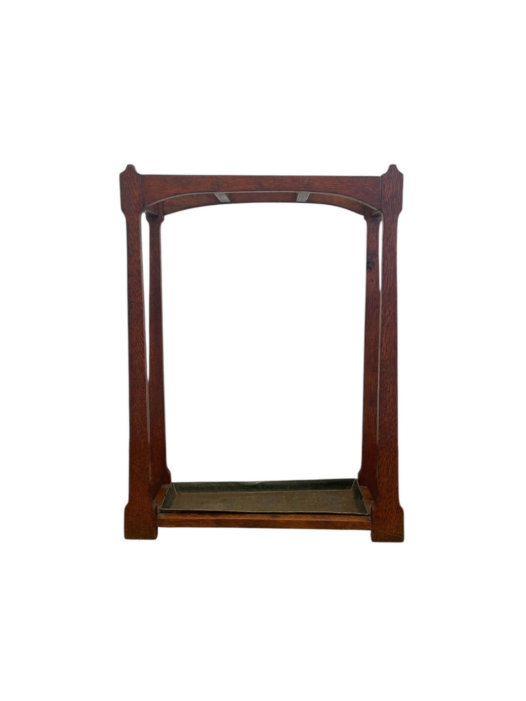 This antique Mission-style umbrella stand dates to the early 20th century and features a solid quarter-sawn possibly oak frame with a warm, rich finish.Characteristic of the Arts & Crafts movement, the stand showcases clean lines, exposed joinery,